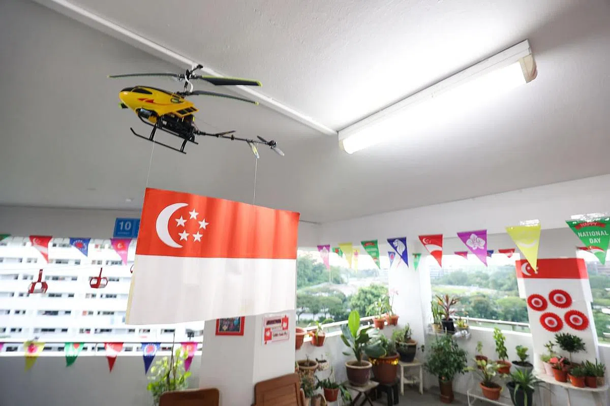 裕廊西组屋居民把国庆典礼搬到家门口，悬挂着国旗的直升机在走廊“飞行”。（李冠卫摄）