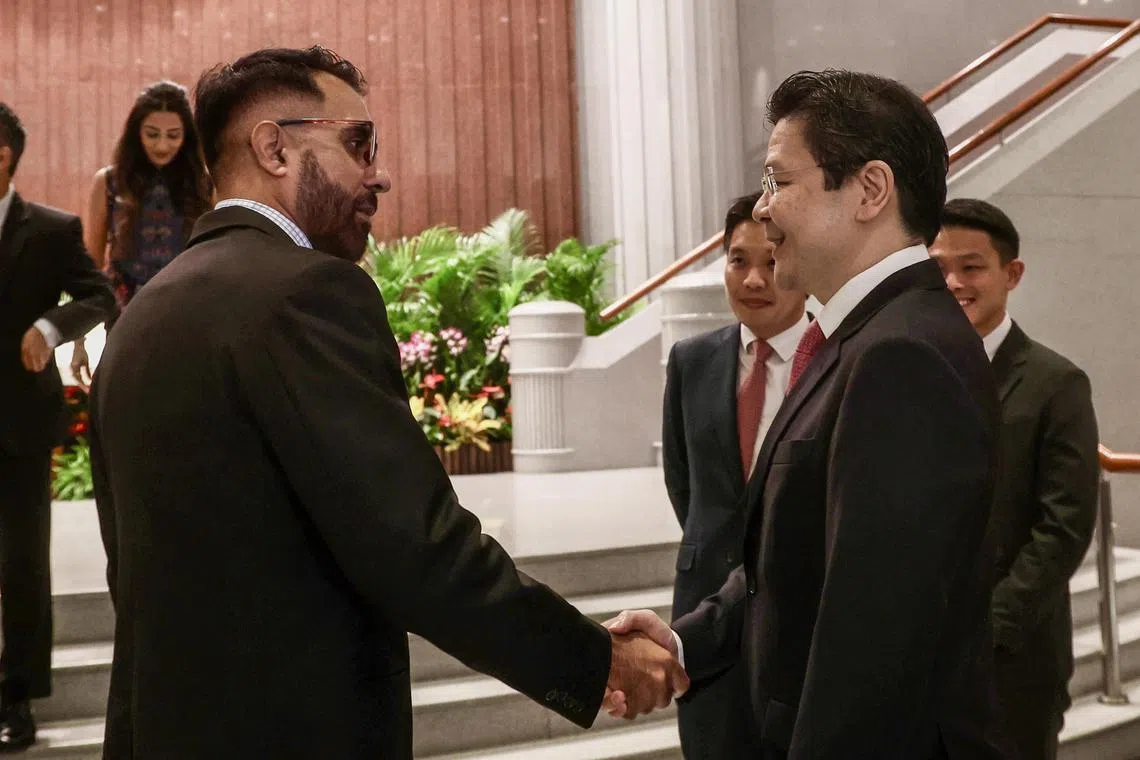 黄循财总理（右）和国会反对党领袖毕丹星在第15届国会开幕场外交流。（邝启聪摄）