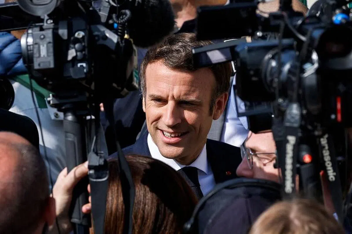 法国总统马克龙在3月28日的一个公开活动中被媒体团团包围。（法新社）