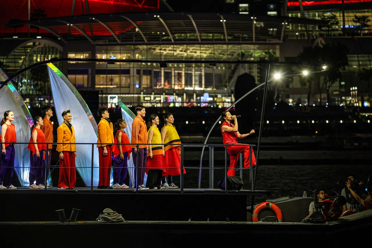 本地歌手金文明首次登船在滨海湾献唱，船上舞者随着音乐翩翩起舞，背景是点亮“SG60”字样的艺术科学馆，映衬出如画般的梦幻氛围。（关俊威摄）