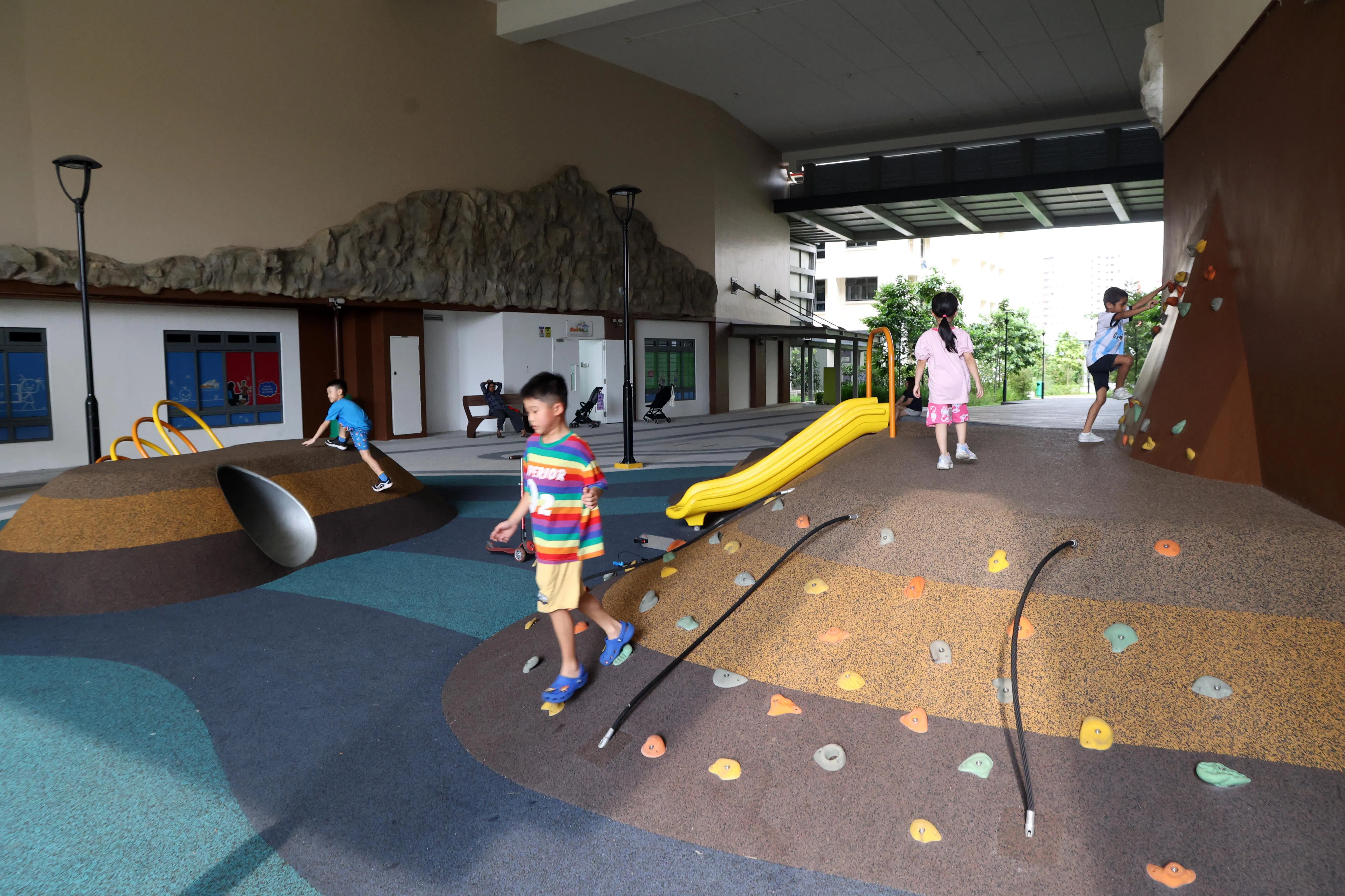 Parc Glen@Tengah的“岩洞游乐场”的地面和墙上都铺满了各种逗趣形状的小岩石，让小朋友沿着小丘坡道上上下下，还能探索攀岩初体验；傍晚时分不少居民带着孩子们到这里玩。（邝启聪摄）