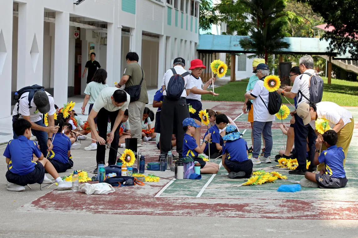星期二（7月22日）下午，武吉知马小学的60名学生也到现场，帮助居民和基层义工完成最后的装饰工作。（何炳耀摄）