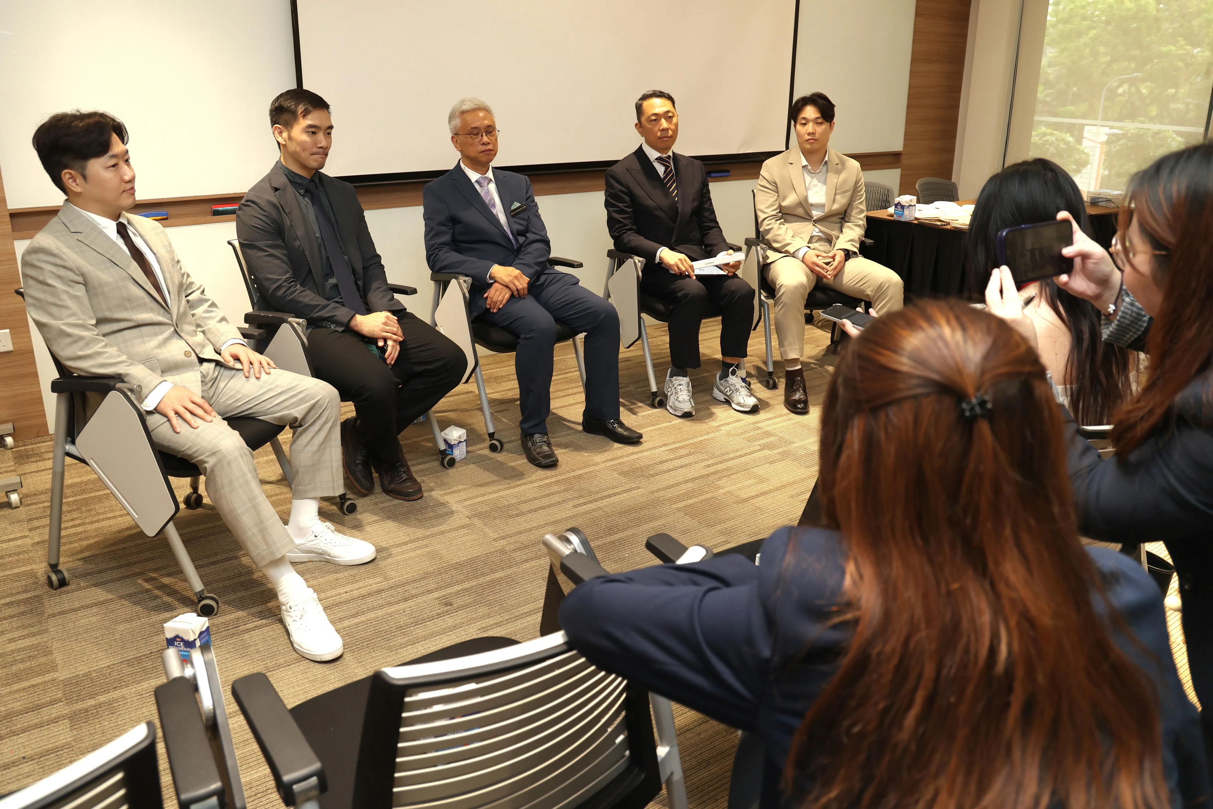 新保综合诊疗所研究与基层医疗研究院主任陈业川副教授（左三）和韩国企业代表接受媒体访问，介绍双方合作的创新科技护理应用。（郑一鸣摄）