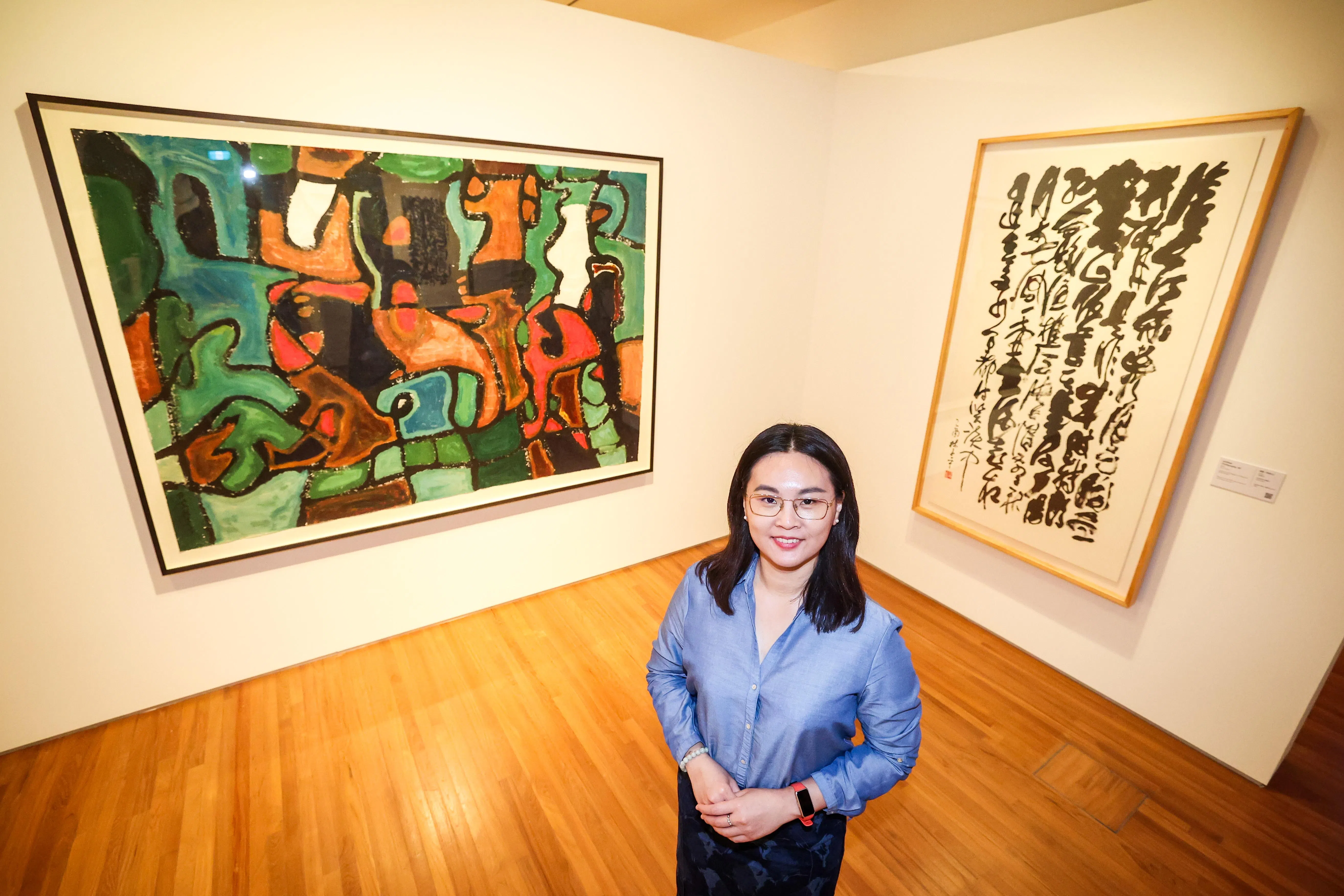 策展人林家欣说，林子平后期的创作字画不分，背后两幅作品均源自明代杨慎《临江仙》词句。（陈斌勤摄）