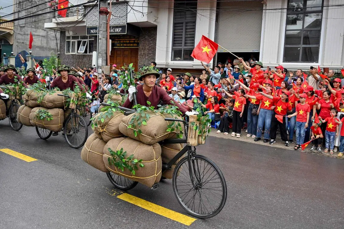 表演者推着脚踏车参加庆典游行。奠边府战役期间，越南人以脚踏车为战场上的士兵提供粮食和物资。（法新社）
