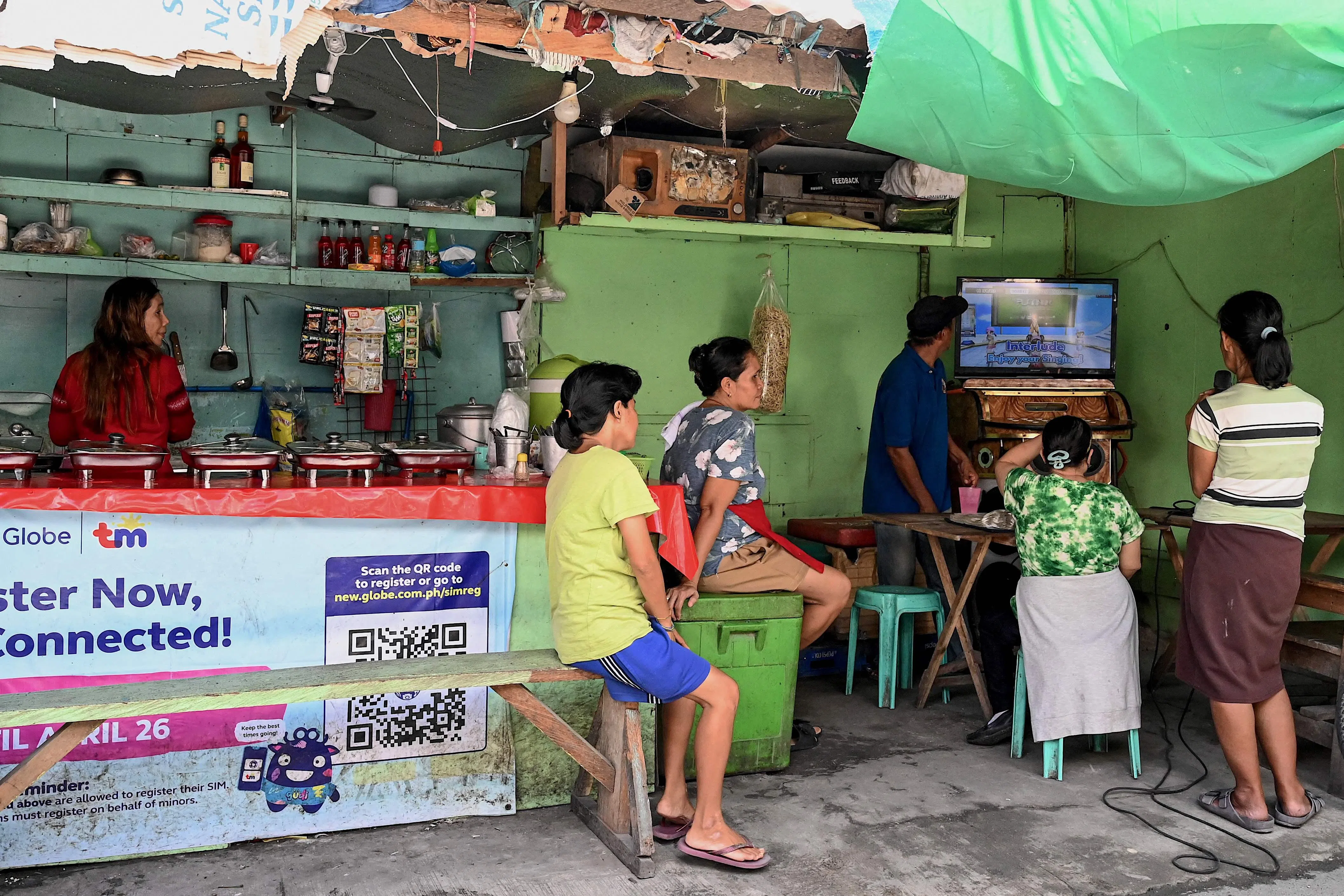 马尼拉许多店家会安装卡拉OK伴唱机，吸引爱唱歌的顾客，增加自己的收入。（法新社）