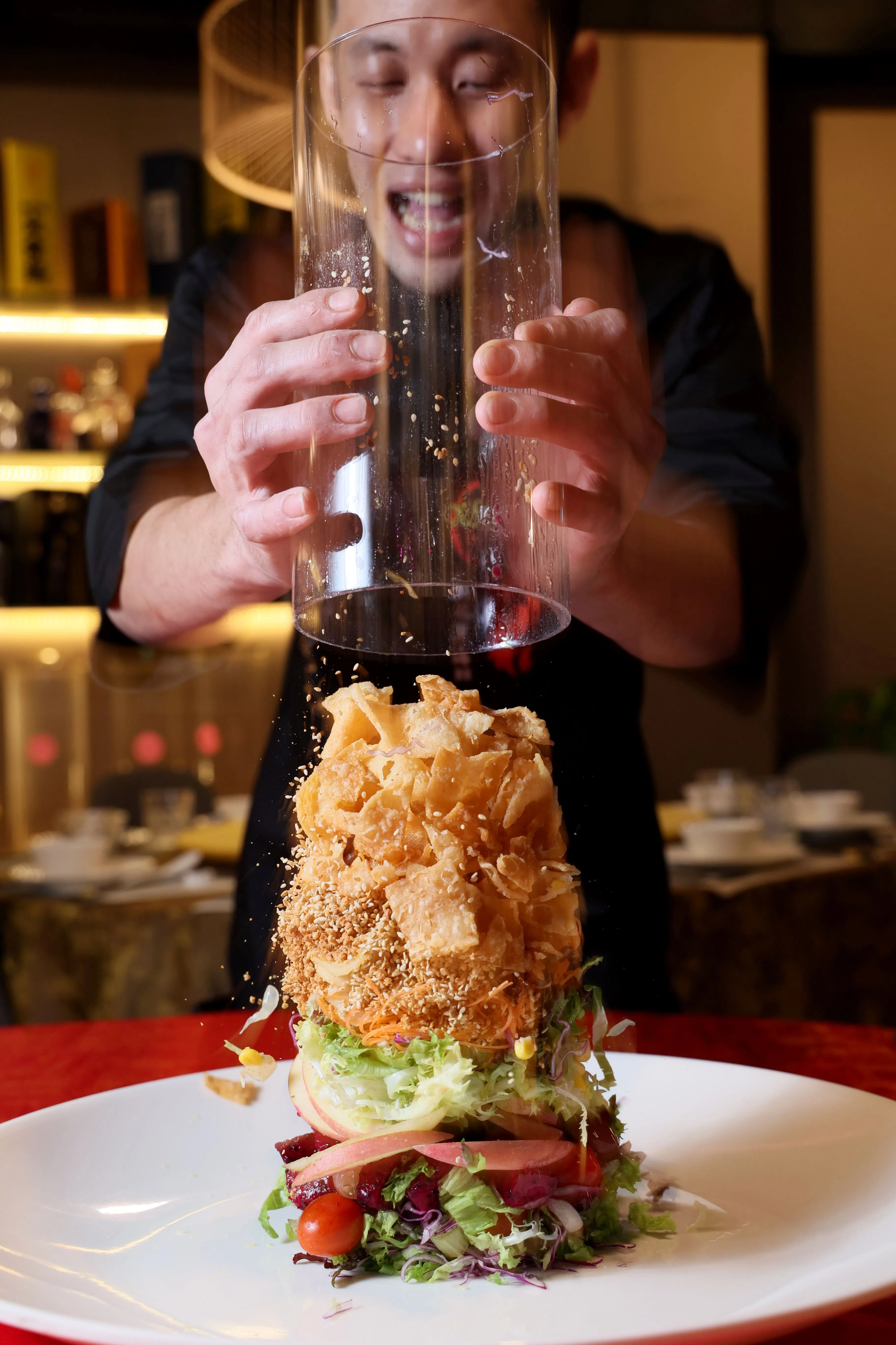 捞生食材放在塑料圆筒里，一声“发啊！”，抽起圆筒，所有好料如瀑布般倾泻到盘里，很有视觉效果。（龙国雄摄）