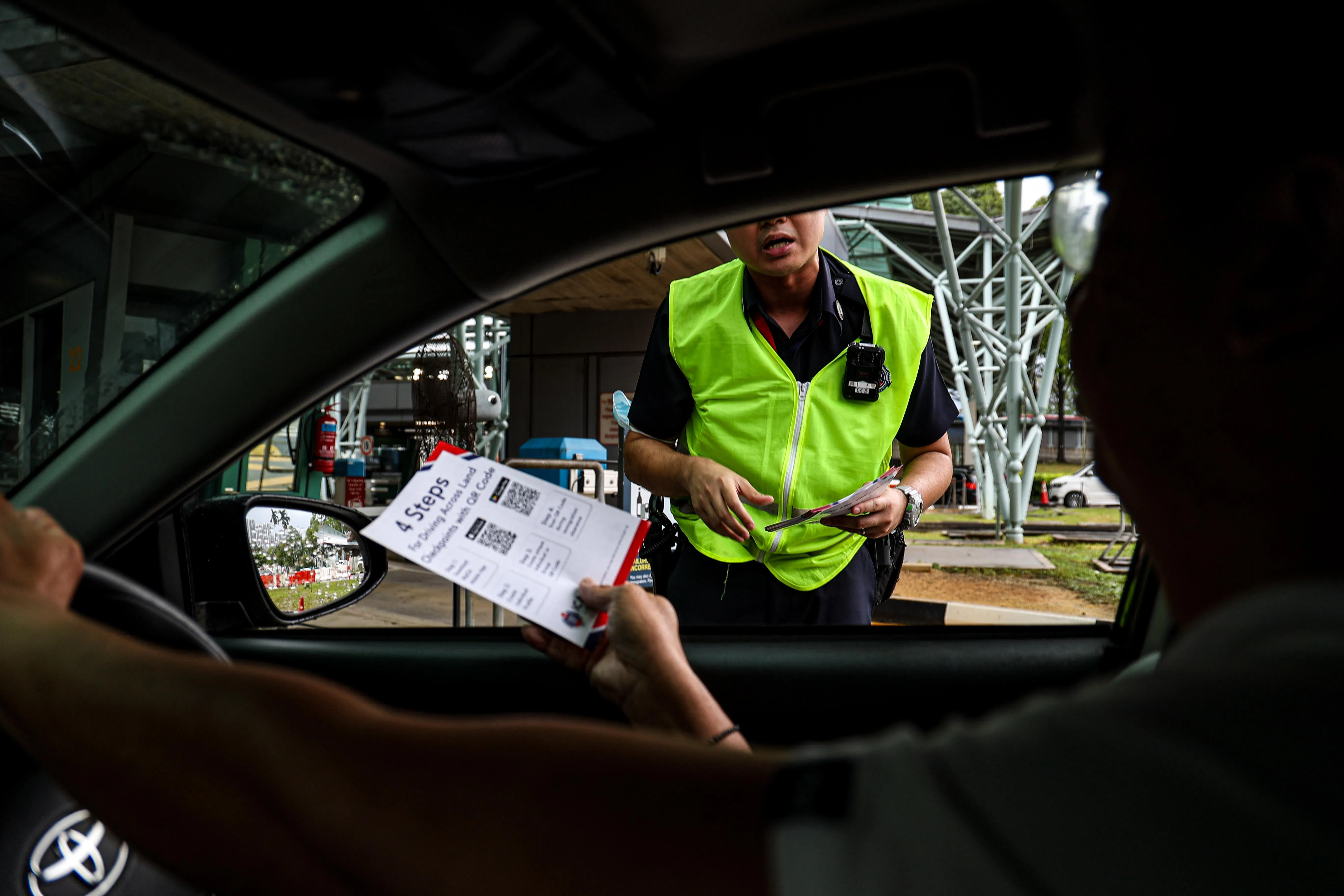 移民局也安排多名工作人员在入境柜台处向开车人士派发传单，鼓励他们采用QR码通行。（关俊威摄）