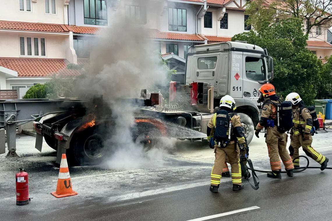 消防员赶来灭火，路面上布满用灭火器灭火时留下的白色粉末，拖车旁还有一个灭火器。（邝启聪摄）