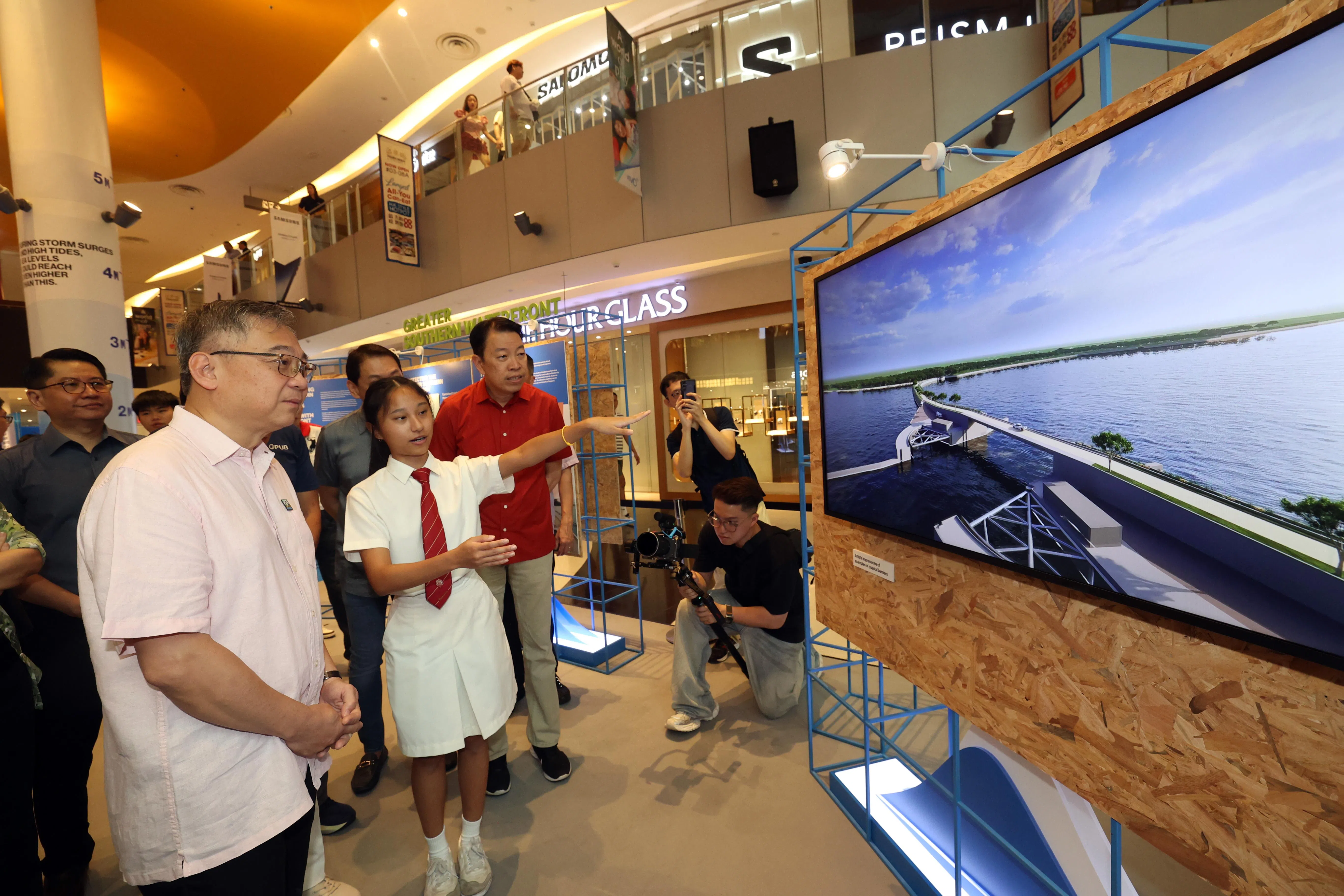 副总理兼贸工部长颜金勇（左一）星期六（8月30日）参观在怡丰城举办的海岸防护展览，观看我国拟议在本岛、圣淘沙和布拉尼岛之间建设的海岸防护墙视频。一起观看的有拉丁马士区议员杨益财（红衣）。（邝启聪摄）