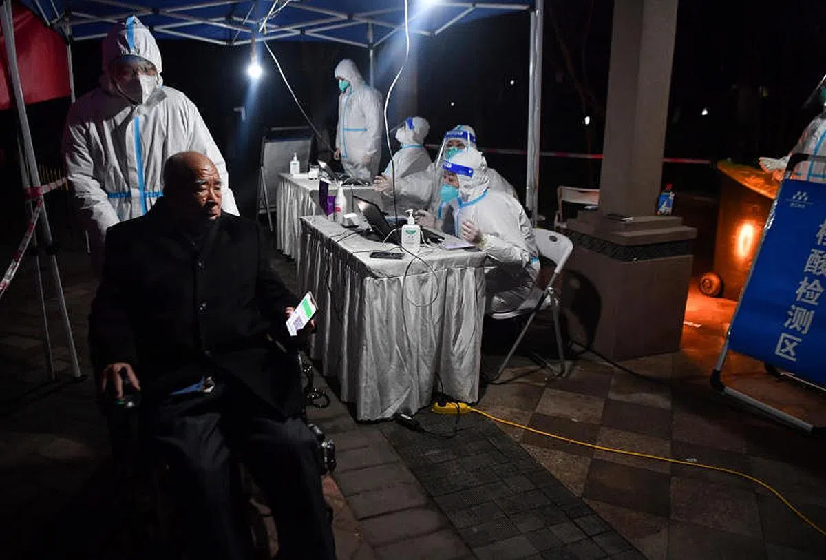 在西安曲江风景线小区，志愿者协助老人进行核酸检测。（新华社）