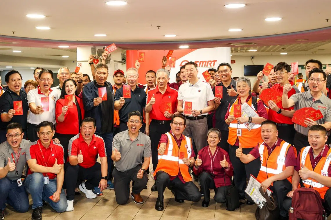 全国交通工友联合会执行秘书杨益财（第二排右五）和SMRT主席佘文民（第二排右六）在顺利巴士车厂，为高级巴士车长许帝贤车长（前排右四、红衣者）等员工分发印有“顺利”的卡片，并合照留念。（陈斌勤摄）