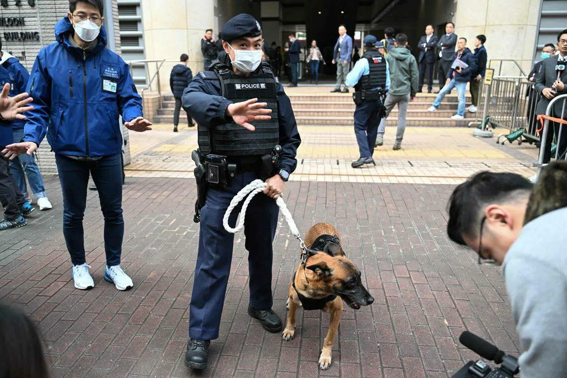 一名警员带着一只警犬星期一（12月18日）上午在西九龙裁判法院外开路。壹传媒创始人黎智英被控违反《香港国安法》案件当天在该法院开审。（法新社）