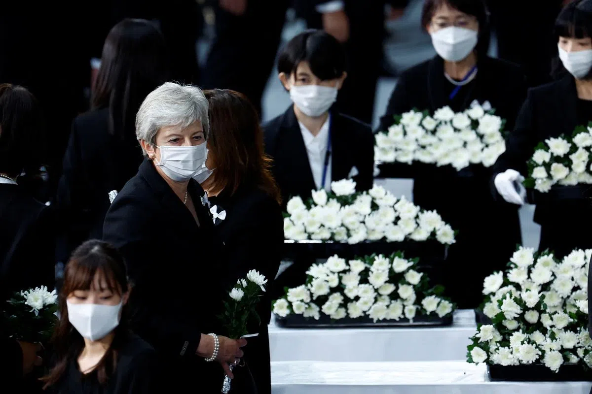 英国前首相特雷莎·梅准备向安倍晋三献花。（路透社） 