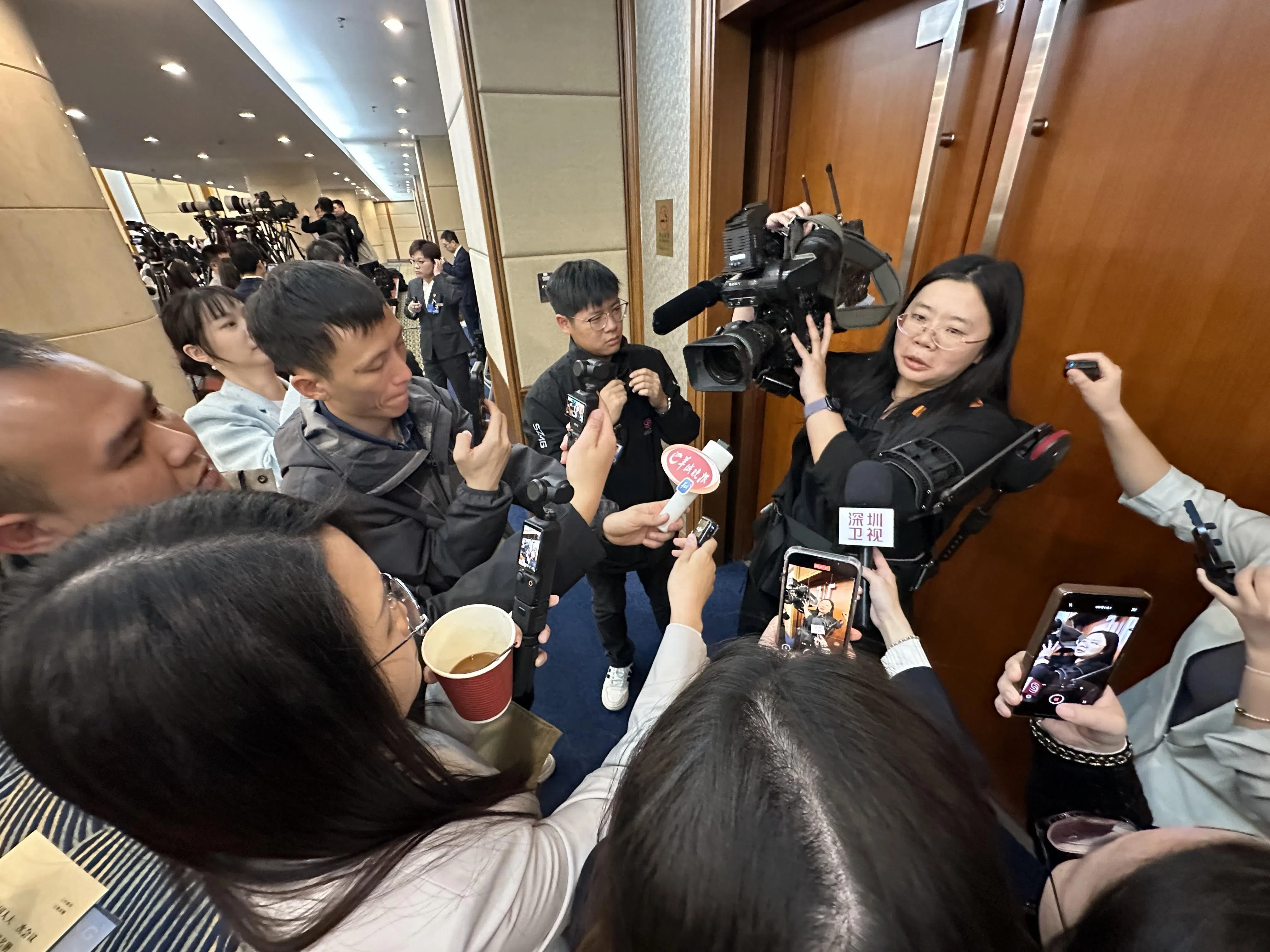 广东代表团展示的外骨骼机器人吸引众多媒体体验，科技装备大幅提升拍摄效率。（林煇智摄）