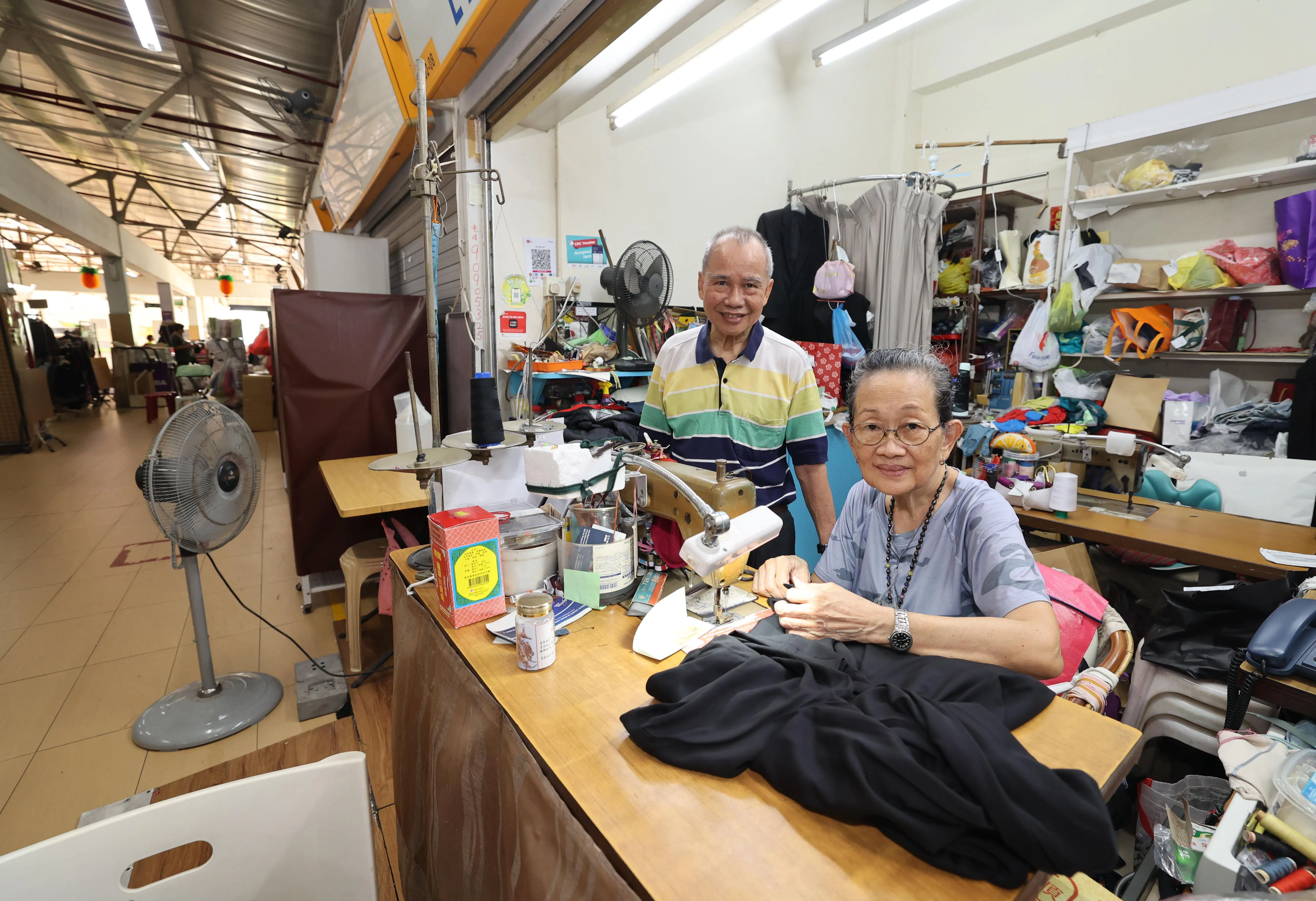 黎本兰（左）和张美琪夫妇俩从1997年就在旧机场路熟食中心二楼开店，为顾客修改衣服。他们希望中心翻新后，能将人潮引上二楼。（邬福梁摄）