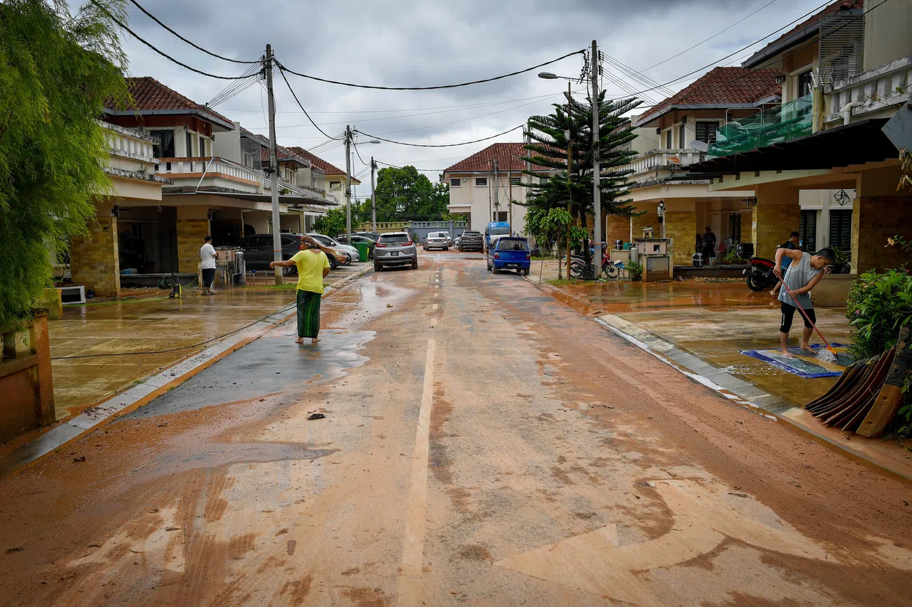 雪兰莪州加影地区的洪水星期五（4月11日）下午消退后，灾民忙着清理屋前的淤泥。（马新社）