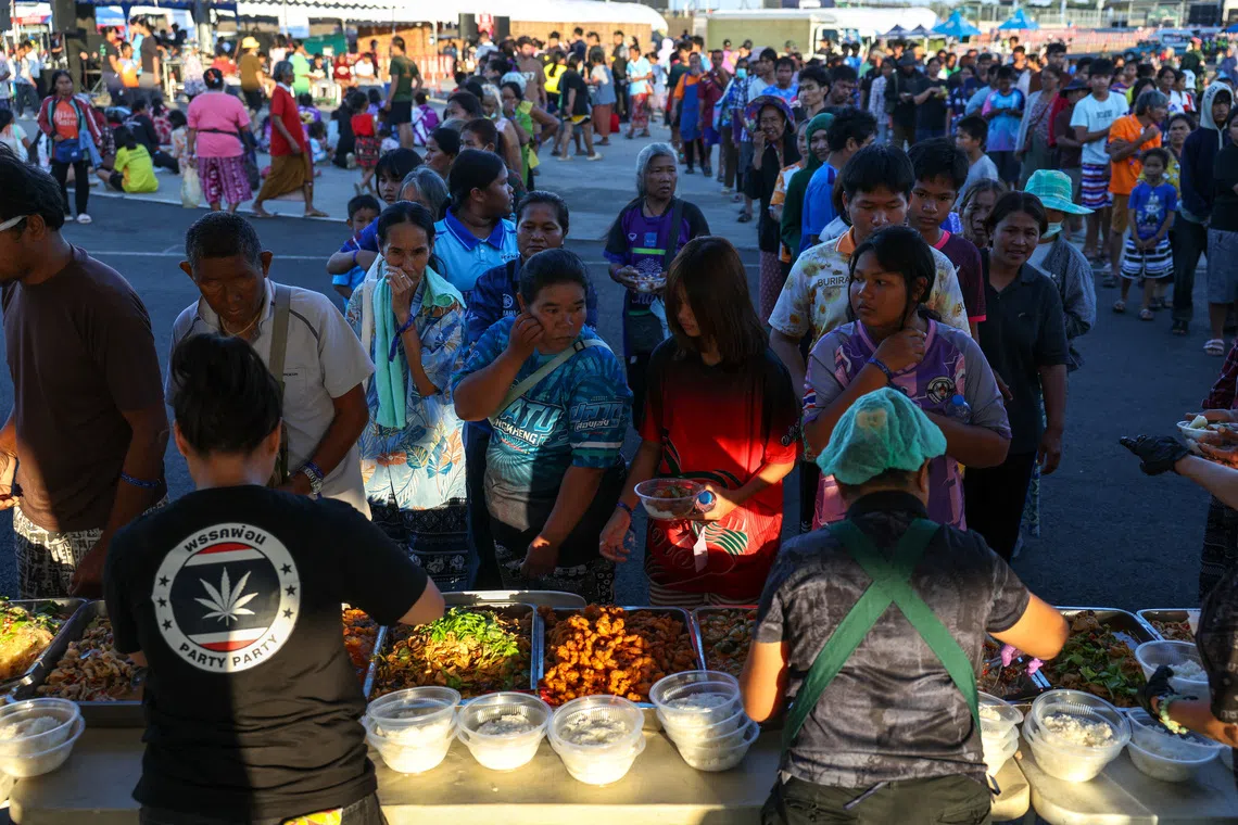 泰柬边境冲突进入第二周，在泰国武里南府，不少流离失所的民众在临时避难所排队领取食物。（路透社）