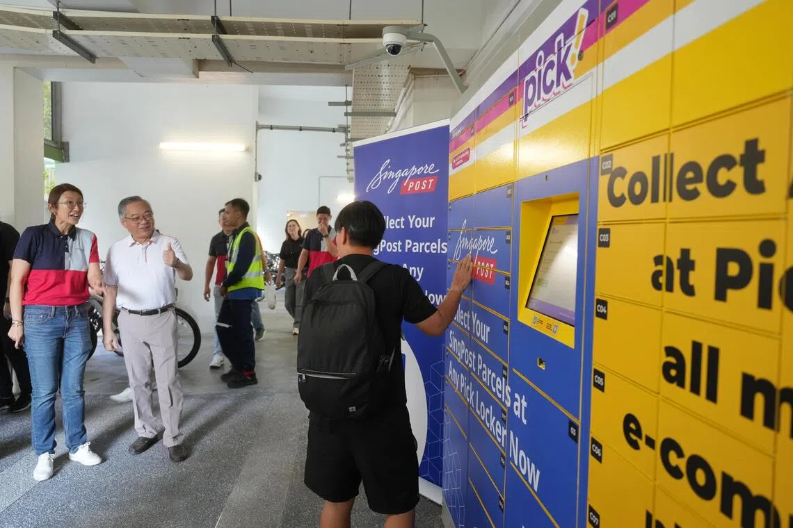 副总理兼贸工部长颜金勇（左二）星期天（10月19日）在榜鹅北岸为“SingPost@MyBlock信箱”试点举行启用仪式。随后也在新邮政集团首席运营官梁舒云（左一）陪同下，参观新邮政和百宝柜（Pick lockers）合作的自提柜服务。他向取件的居民比赞示意。（谢智扬摄）