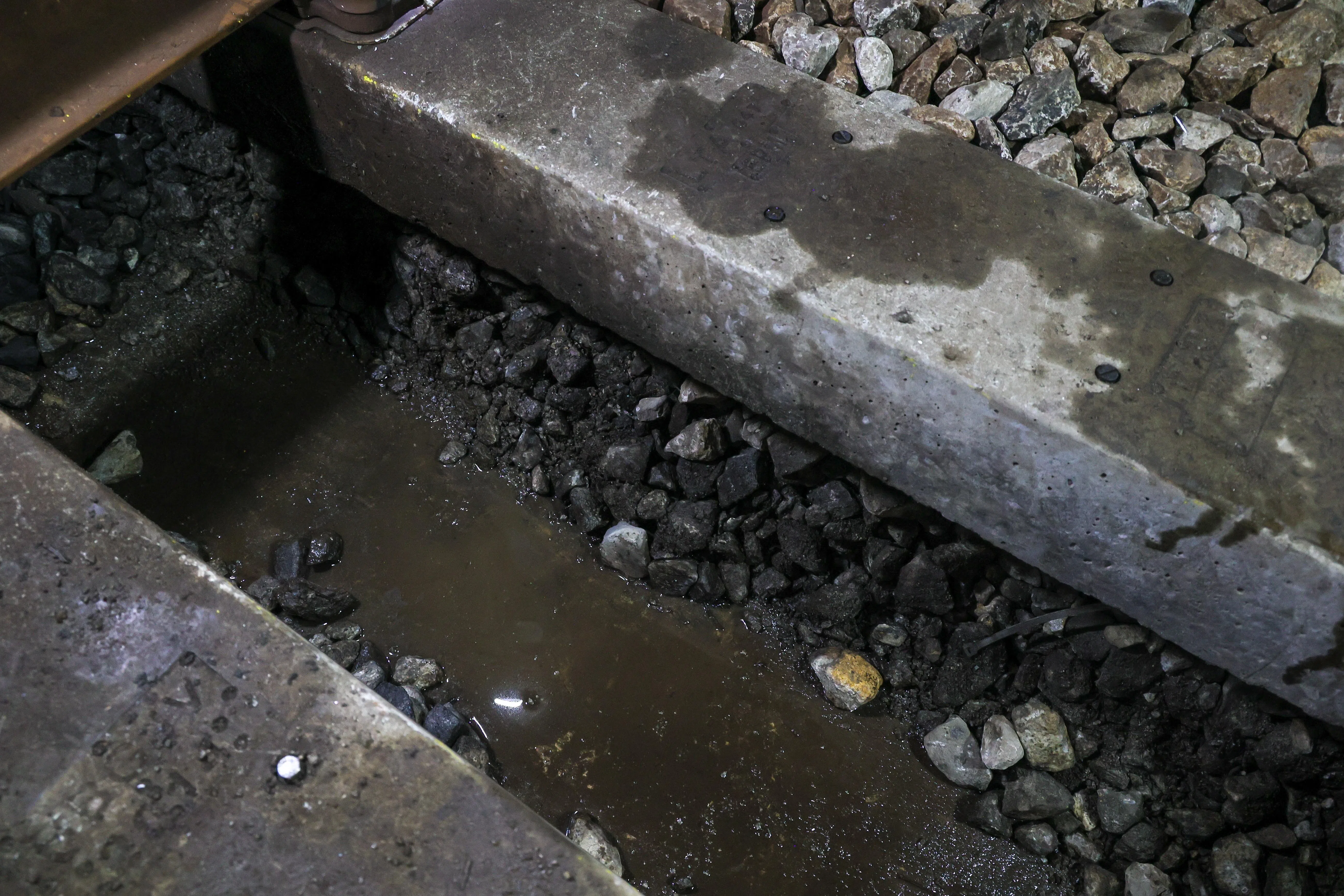 维修人员从两根轨枕之间挖出退化的碎石后，轨道基床暂时呈现空置状态，等待填入新的碎石。（张俊杰摄）