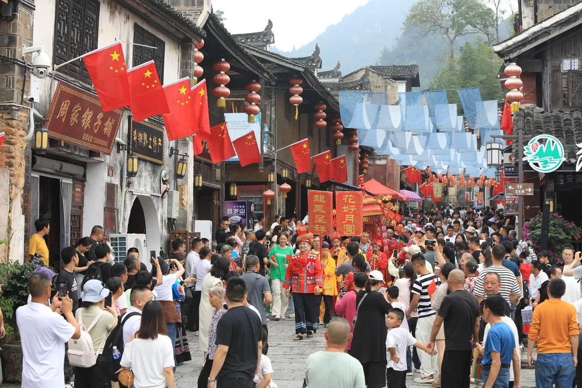 游客星期三（10月1日）在重庆市秀山土家苗族自治县洪安古镇老街观看土家婚俗展演。（新华社）