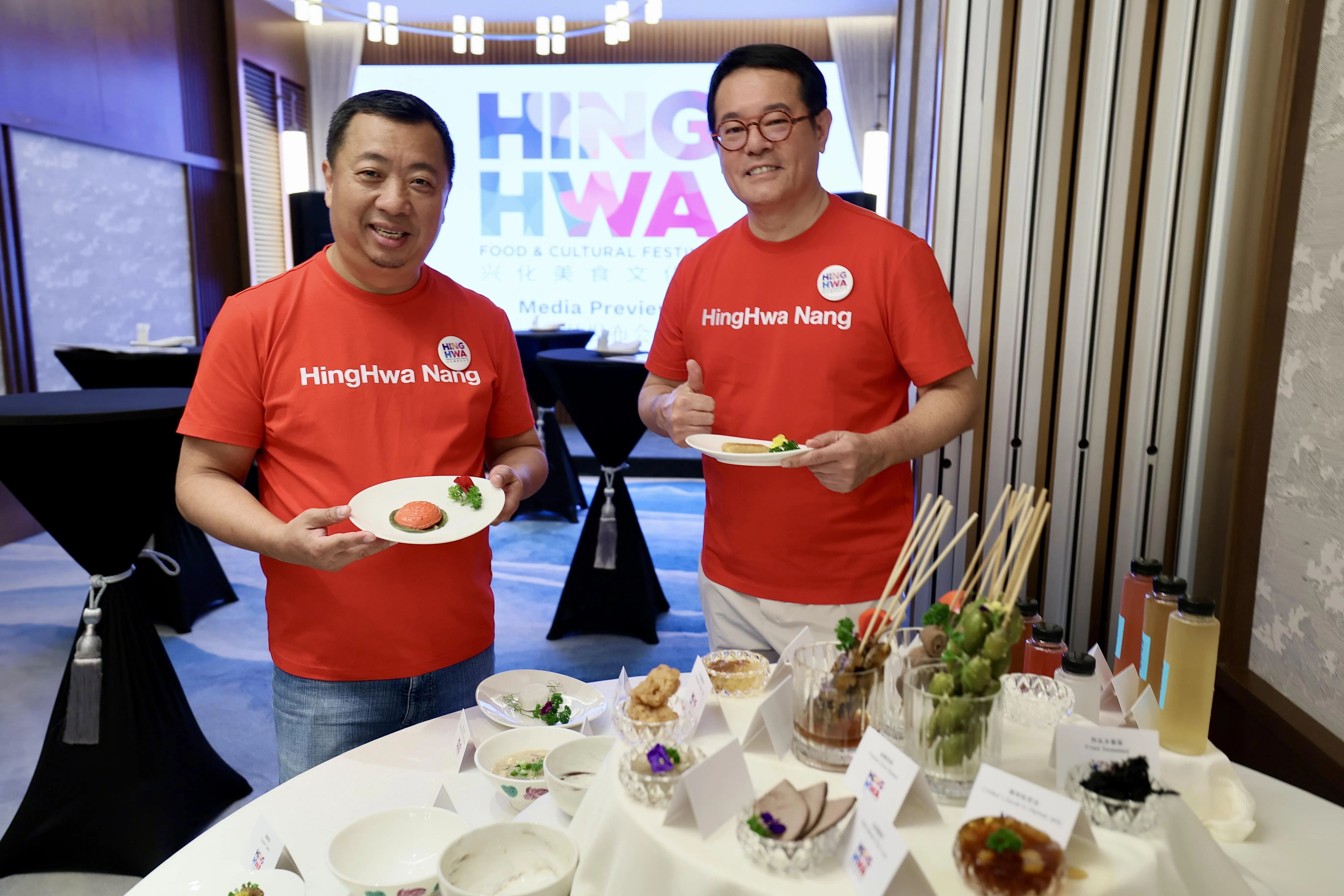 “兴化美食文化节”新闻发布会当天，莆仙联合会会长方志忠（左）和副会长周家萌所穿的红色T恤，上面印着“Hing Hwa Nang”（兴化人）三个大字。（龙国雄摄）