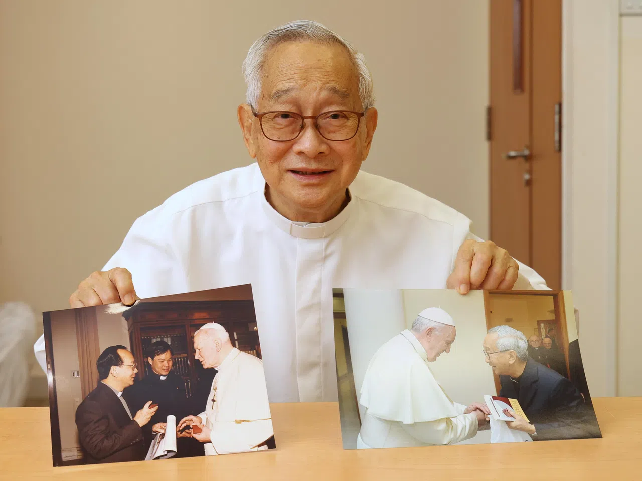 何光辉神父展示1993年与教宗若望保禄二世面对面交流（左边照片），以及他在2018年获现任教宗方济各接见时所摄的照片，两次接见都是在梵蒂冈。（唐家鸿摄）