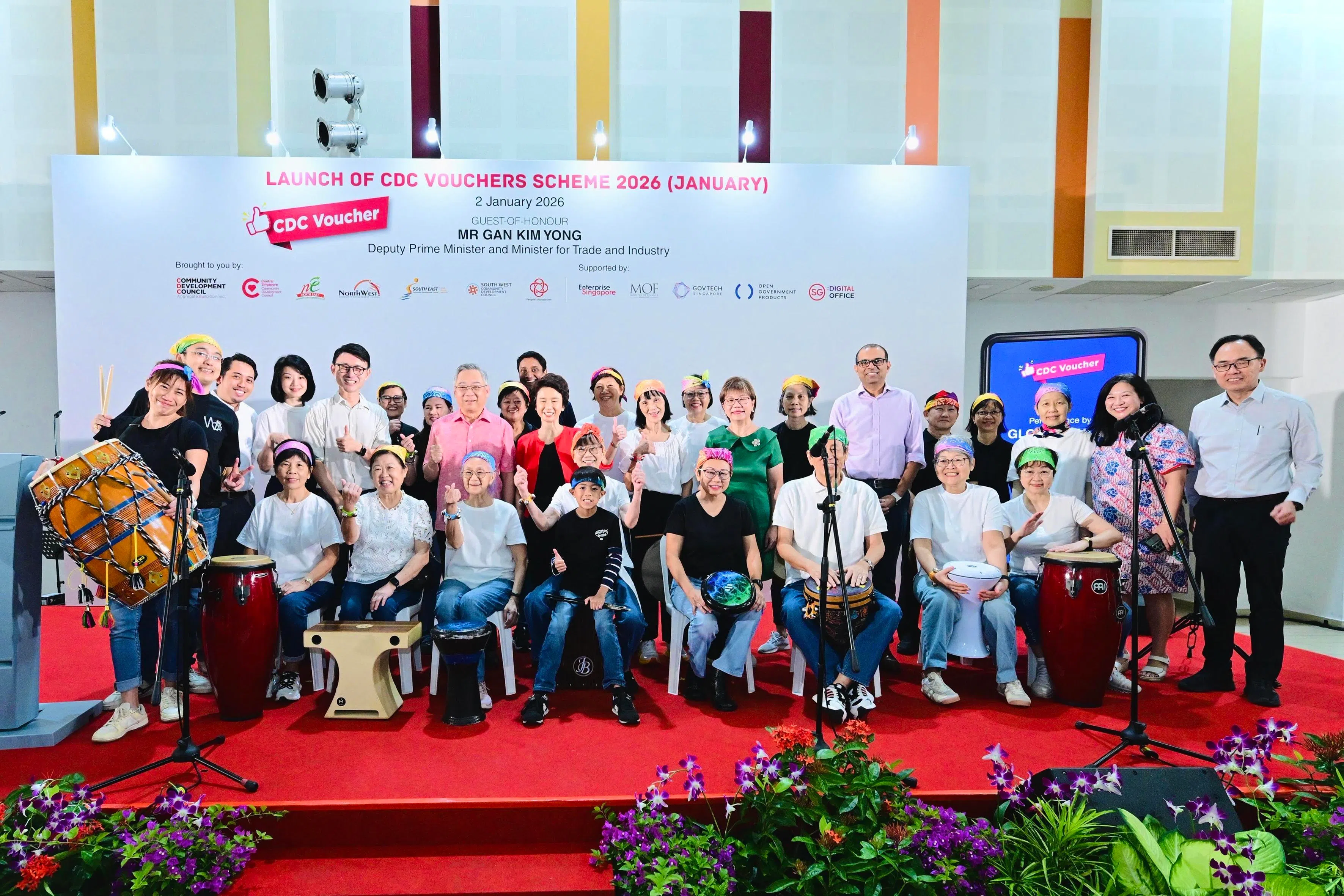 75岁的曾翠莲（坐者左三）今年1月初在社区发展理事会邻里购物券推介仪式上表演后，与鼓队“全球脉动：节奏合一”团友，一起和副总理兼贸工部长颜金勇（站者粉色上衣）等人合照。 （东北社理会提供）