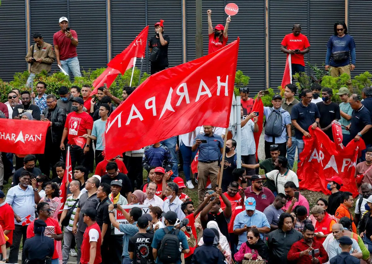 马国新任首相安华的支持者手持希盟的党旗，星期四（11月24日）聚集在国家王宫外，庆祝他宣誓就职。（路透社） 