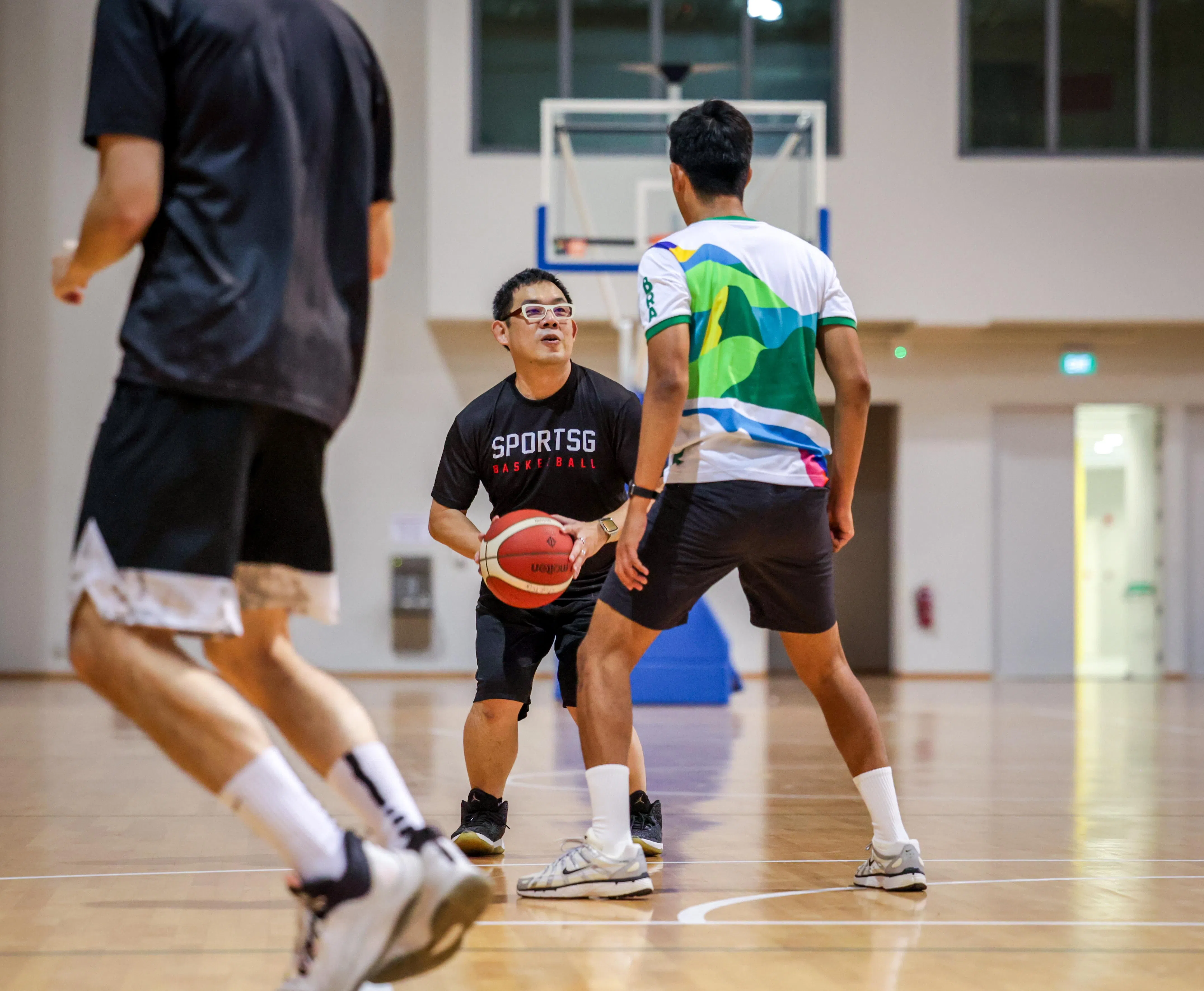 我国体理会总裁吴钦华（中）在接受《联合早报》访问前，先和本地媒体切磋篮球共乐。（叶振忠摄）