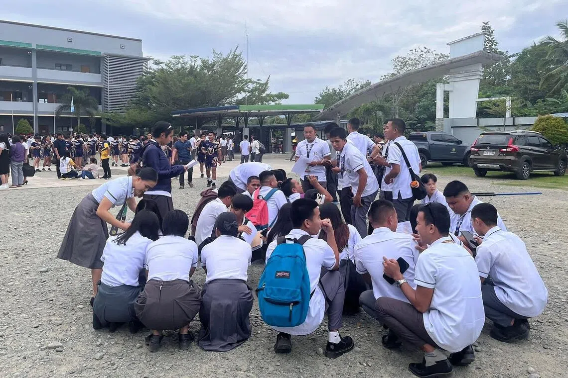 在菲律宾东达沃省，当地一所大学的学生在地震发生后，聚集在学校大楼外。（法新社）