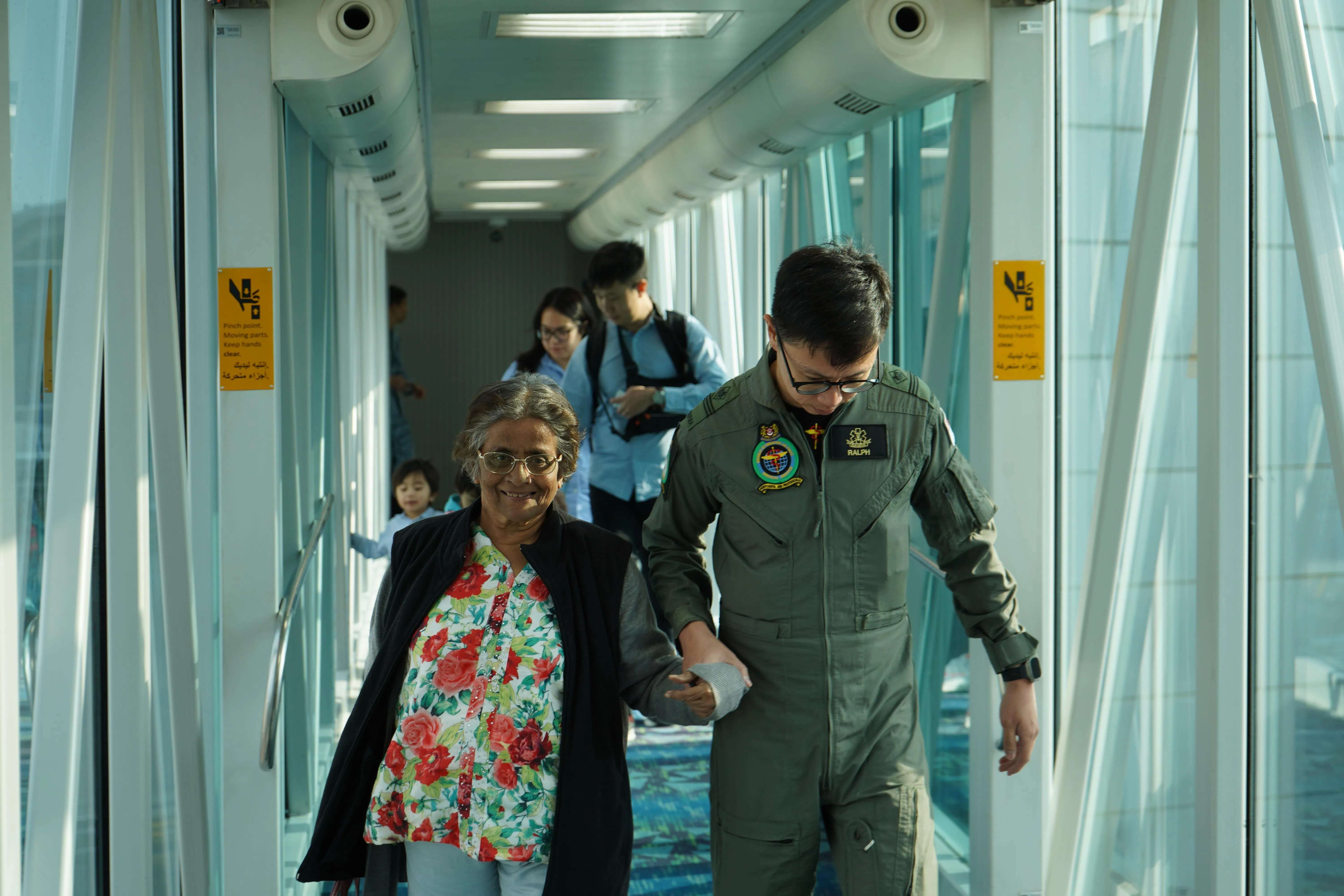 空军部队人员协助乘客登机。据了解，所有乘客必须先在空桥上通过金属探测器，才能登机。（国防部提供）