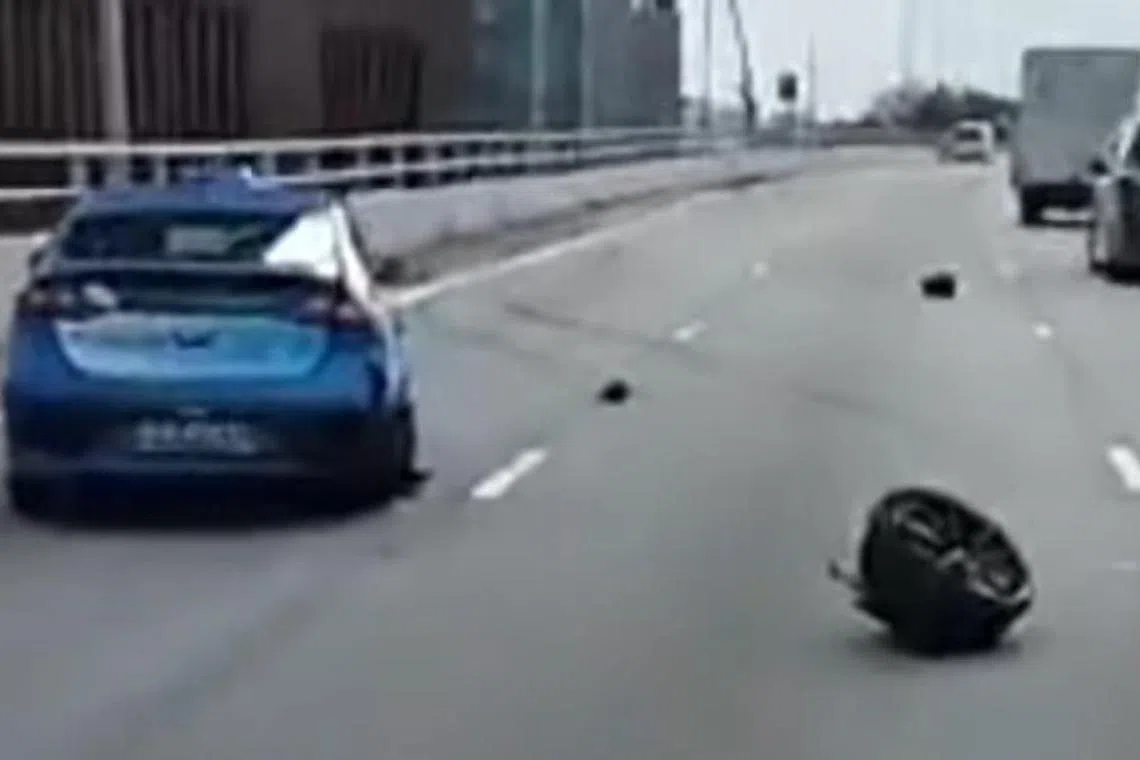 事发后，跑车的一个车轮被撞飞，滚落在路中央。（视频截图）