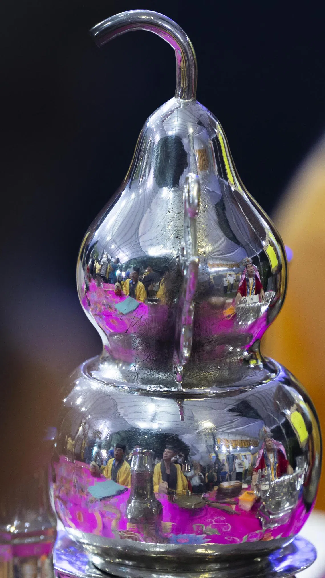 用来收集幽灵的葫芦，映出正严肃诵经超度亡灵的喃呒团队。（龙国雄摄）