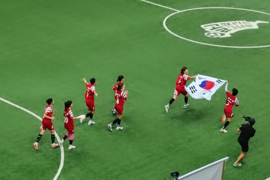 韩国主将朴志晏（红衣右二）攻入第二球后，和队友们拉起国旗庆祝。（陈明耀摄）