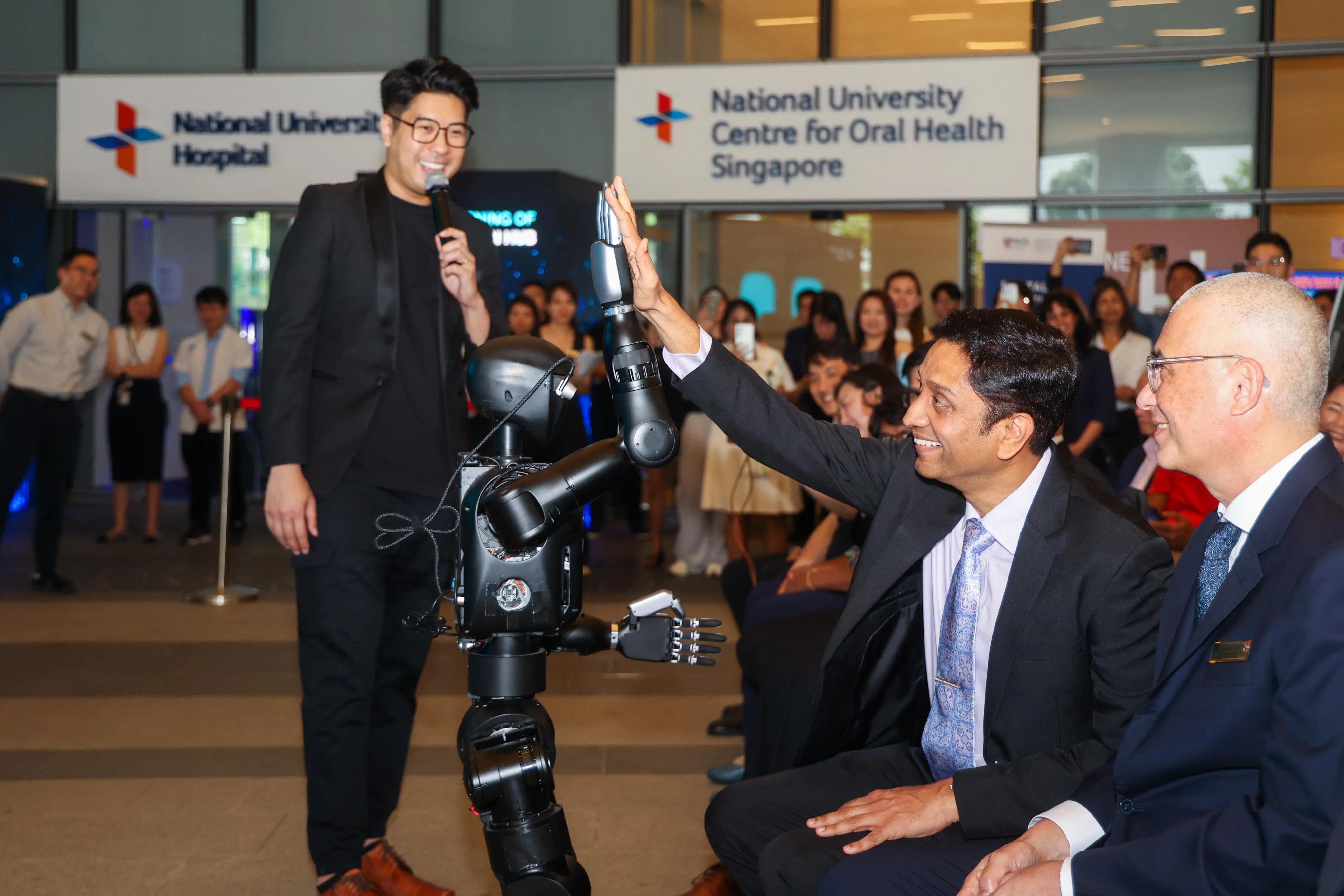 国大医院创新中心的开幕式上，一个人型机器人和活动嘉宾人力部兼文化、社区及青年部政务部长迪内希（右二）击掌互动。（吴先邦摄）