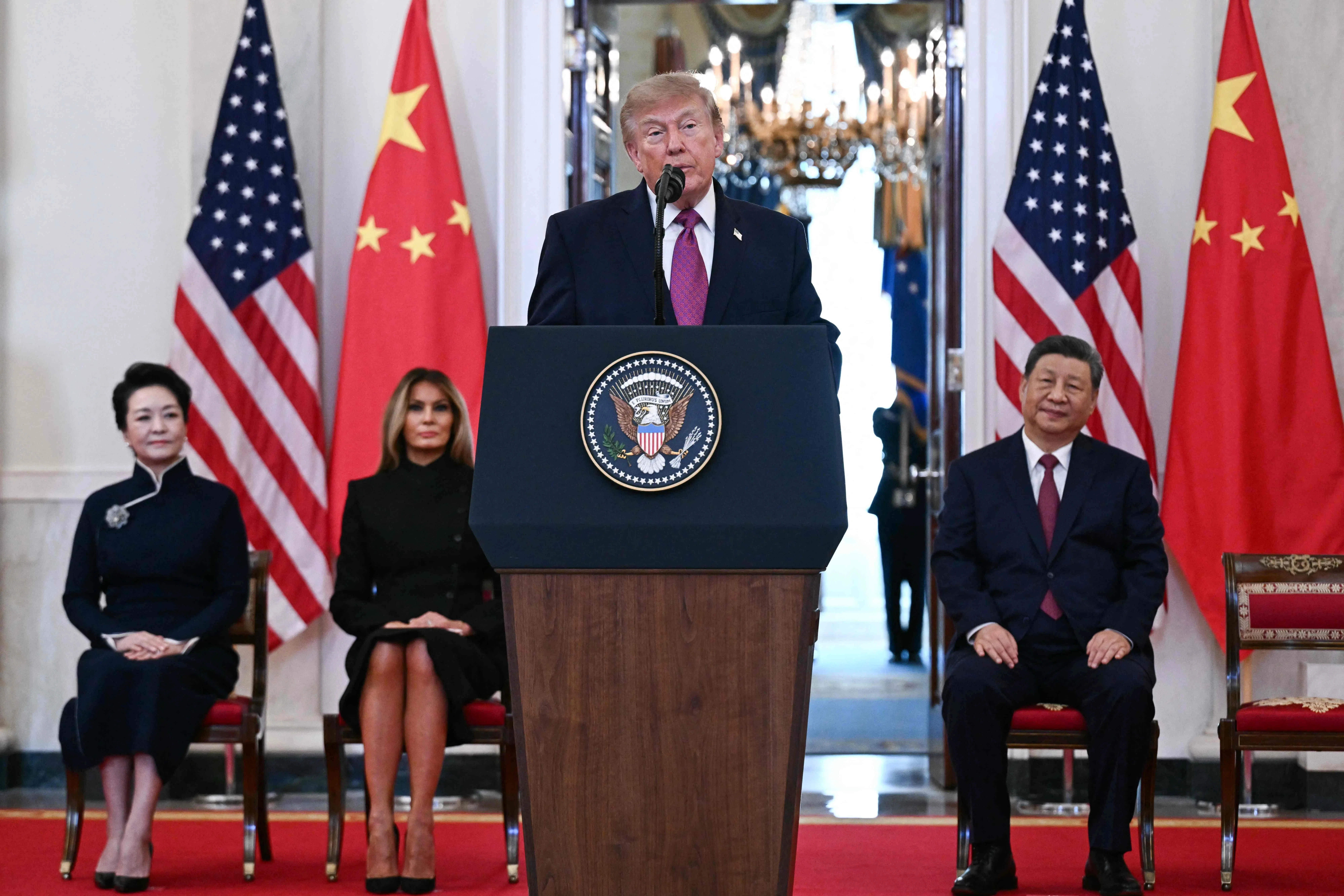 特朗普在白宫十字大厅发表讲话，习近平、梅拉尼娅和彭丽媛在旁聆听。（法新社）