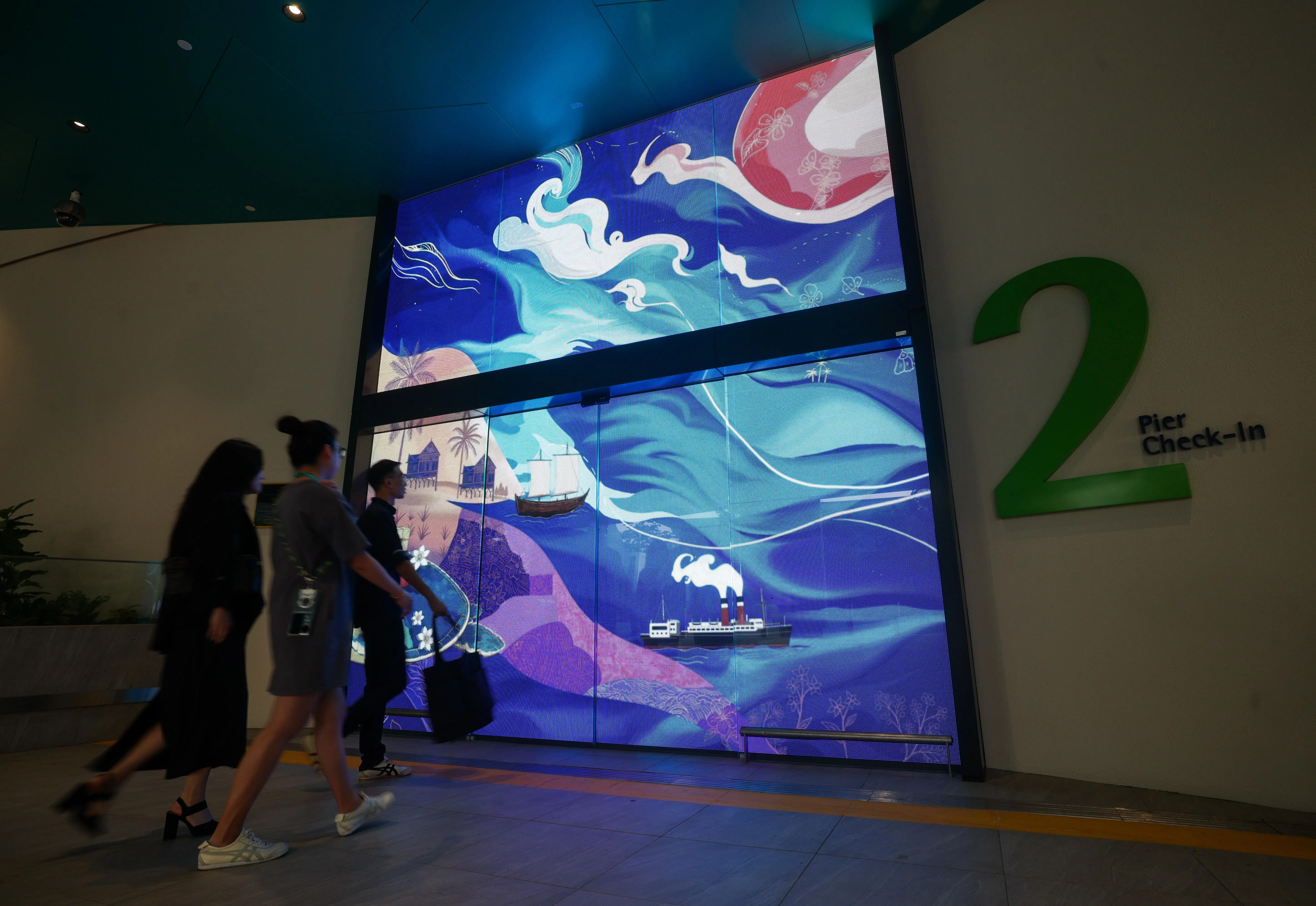 滨海湾游轮中心第二个登船接待大厅的智能玻璃门上，展出壁画的动画版本。（陈渊庄摄）