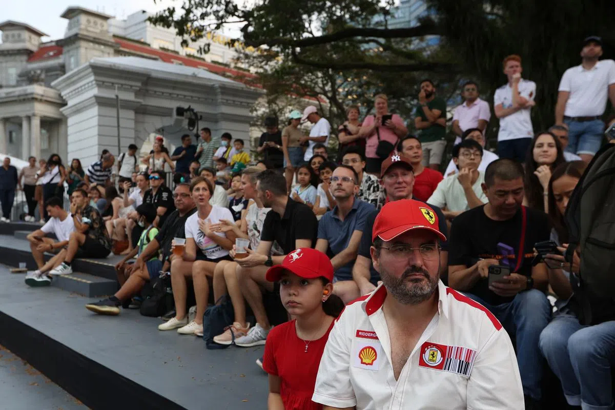 车迷们耐心地坐在在富丽敦酒店外等待赛车经过。（张思庆摄）