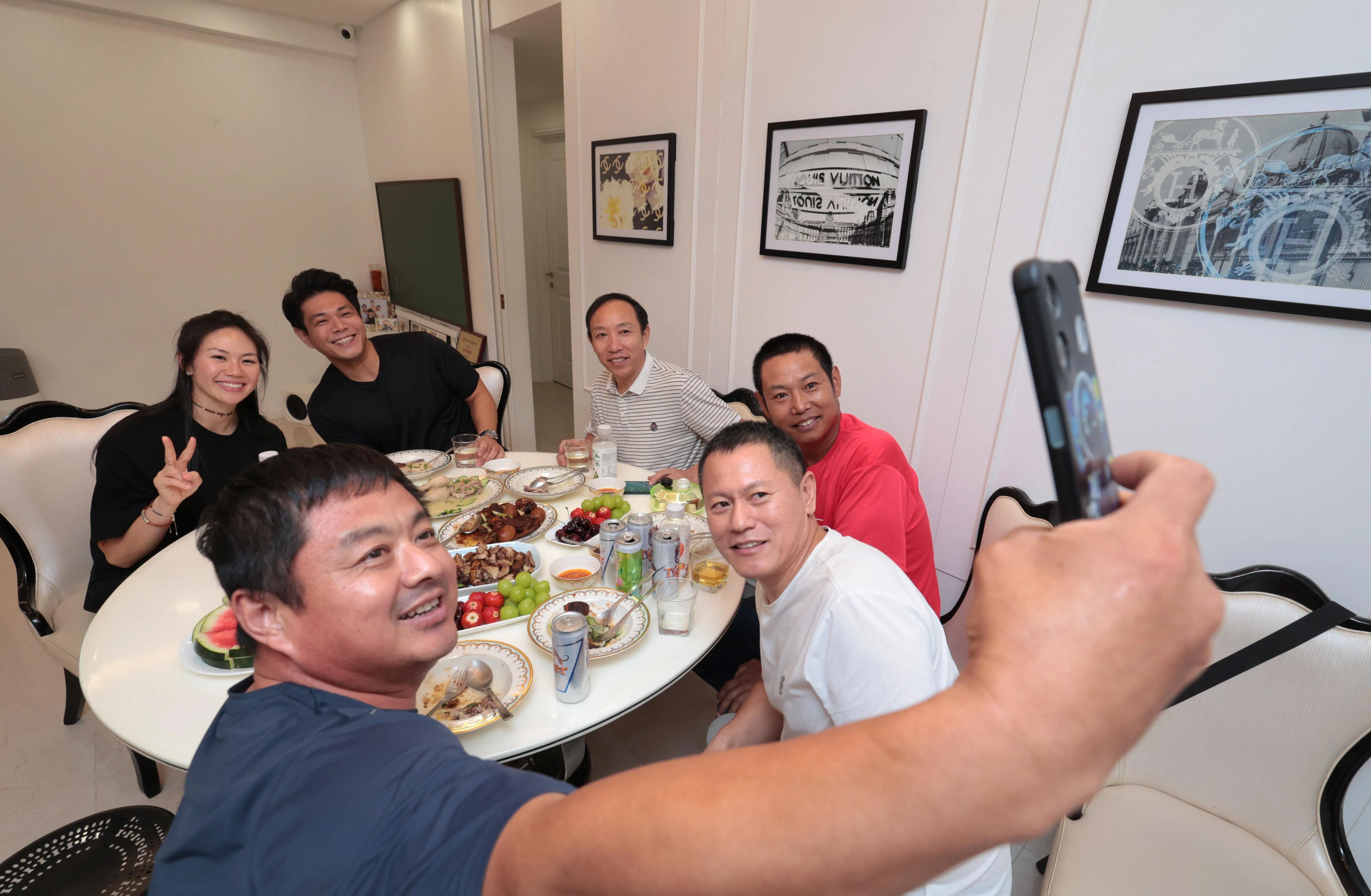 来自中国山东的客工侯庆存（自拍者），在黄子洋夫妇家用餐时，举起手机和大家自拍留念。（梁麒麟摄）