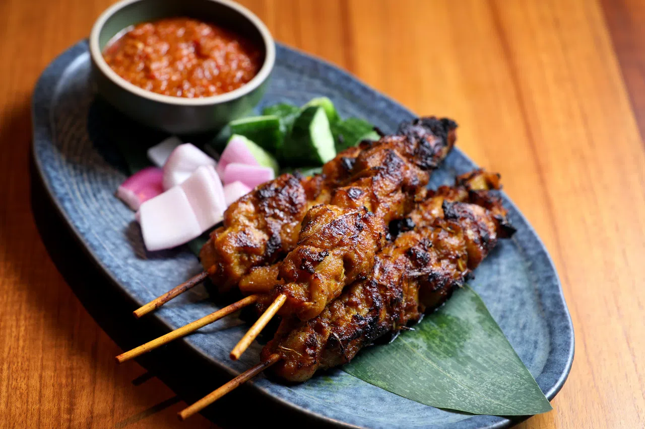 鸡尾沙爹串经炭火炙烤后，鸡尾外层油脂被逼出，表皮微焦酥脆，散发出浓郁炭香味。（龙国雄摄）