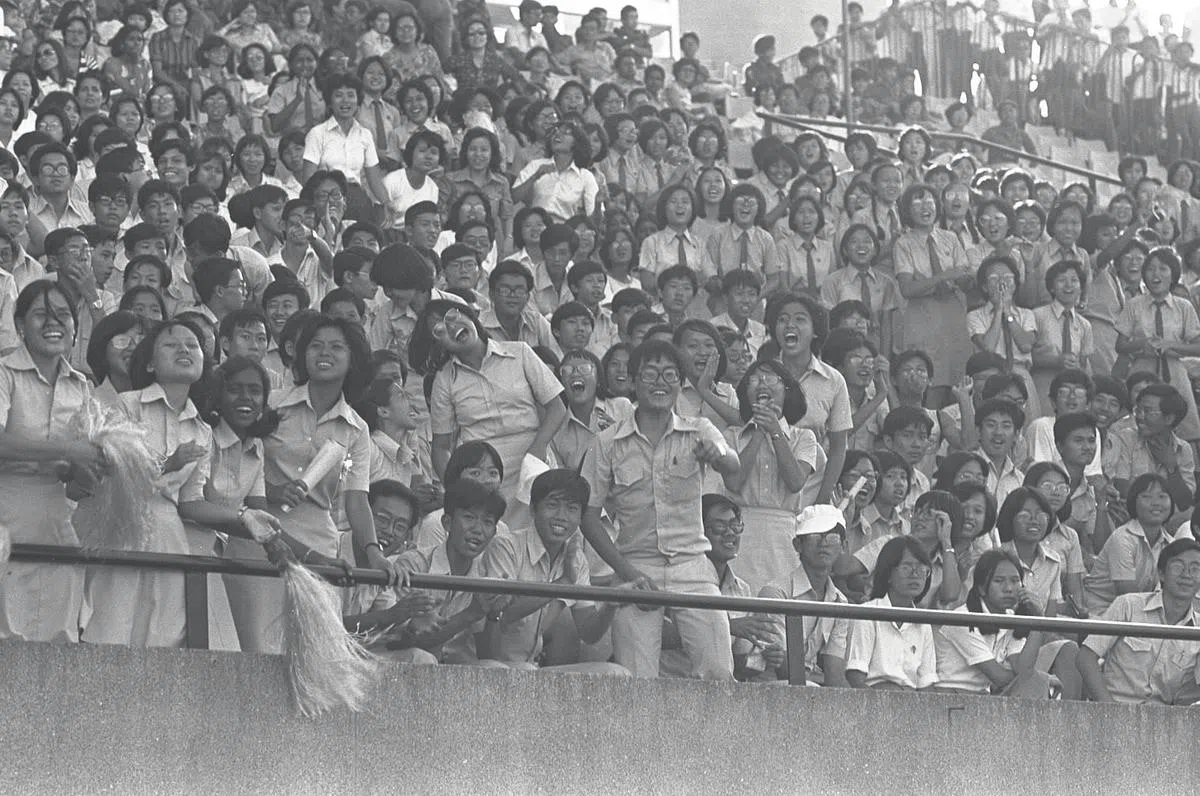 1977年校际田径比赛举办时，旧国家体育场迎来了多名为支持各自学校校队前往观看比赛的学生，座无虚席。有些学生十分兴奋，有些却显得有些失落，情绪被比赛的过程与结果紧紧牵动。（图/海峡时报）