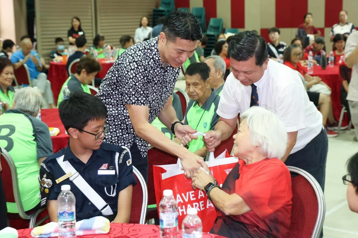 来自三个不同社会组织的约50名年长者聚集活动现场，一一从文化、社区及青年部代部长梁振伟（站立者，左）手中接获爱心礼物。（关俊威摄）