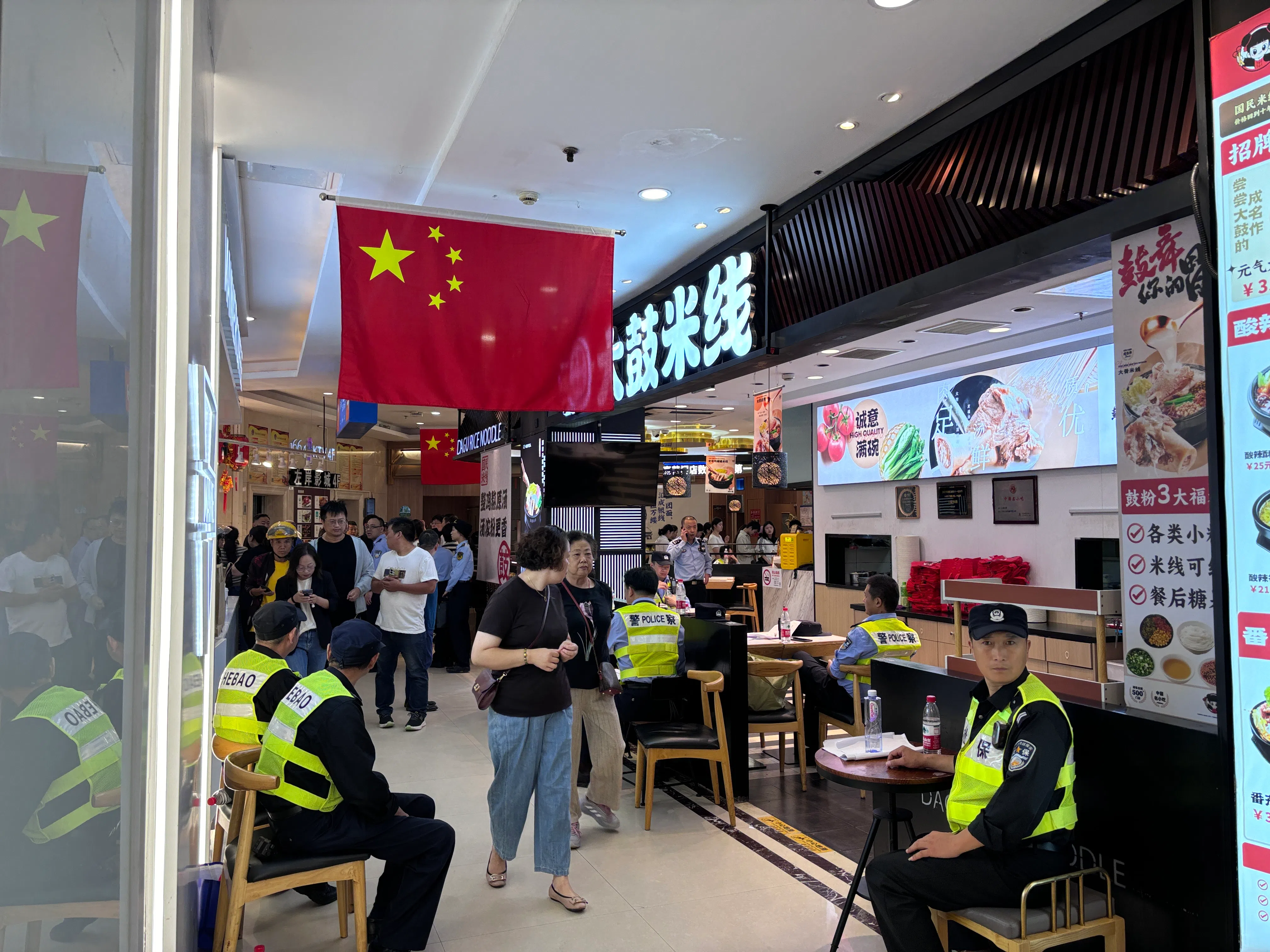 案发商场恢复营业后，入口处坐着多名警察和安保人员。（黎康摄）