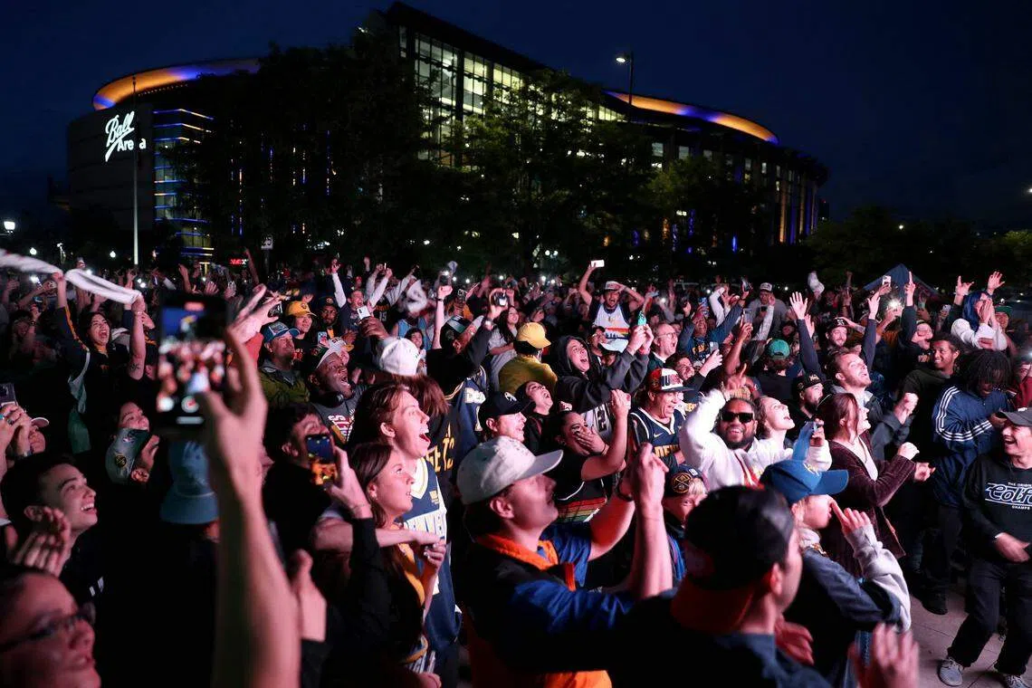 聚集在大电视前观看赛况的球迷为丹佛首夺NBA总冠军欢呼。（法新社）