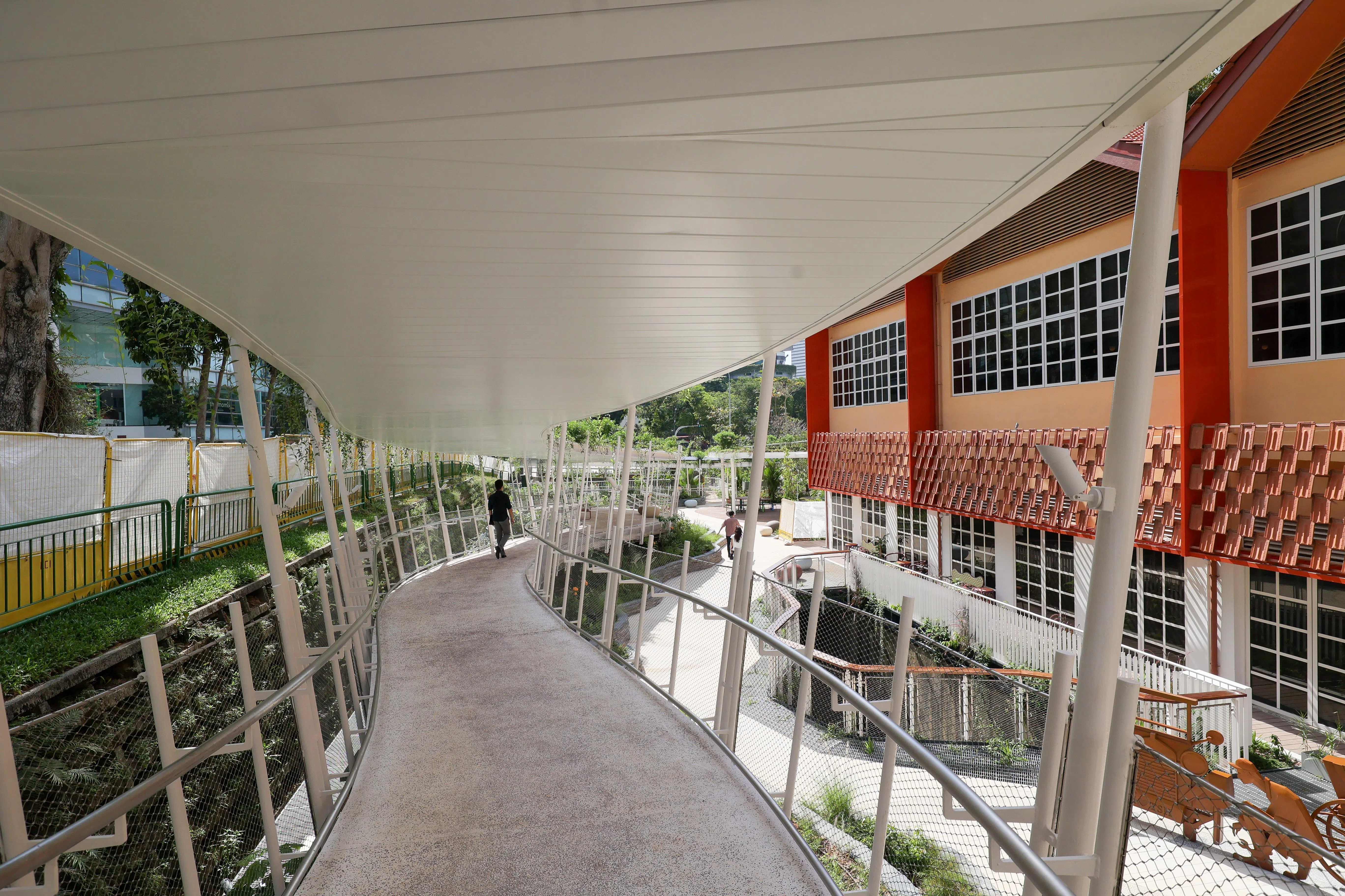 走在有盖走道，顶上是太阳能板和绿植，脚下是用原建筑屋顶上的废弃瓦片磨碎后、掺入混凝土铺设成的走道。（张俊杰摄）