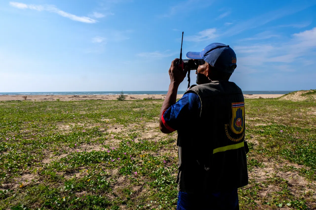 2024年12月2日，班雷在泰国南部攀牙府的班南肯海岸，用双筒望远镜观察海浪。（路透社）