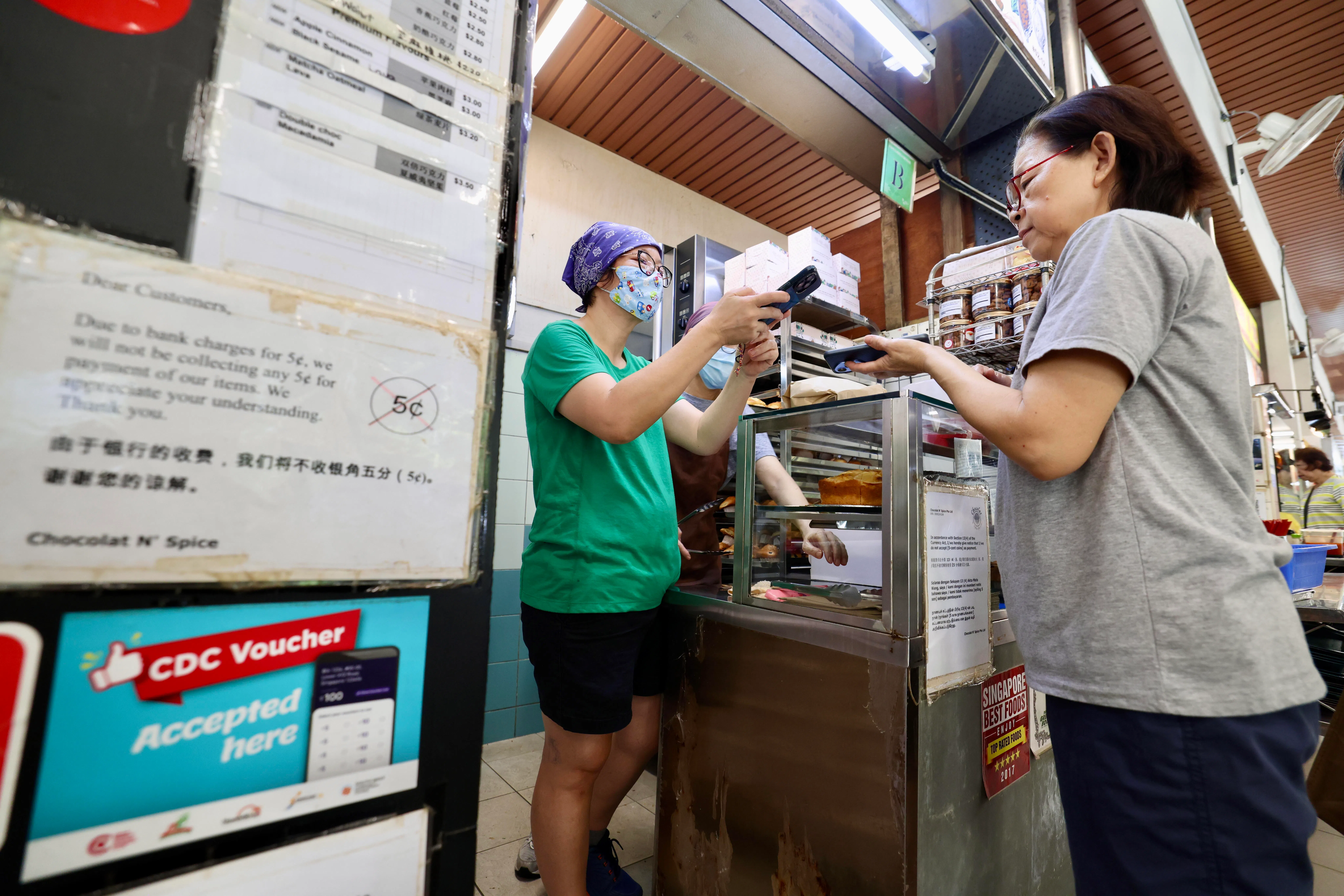 陈佩晶（左）说，这个月有年长者带纸本邻里购物券来买松饼，多数一次购买多个，用来送亲友或一次过凑足购物券额度。（陈斌勤摄）