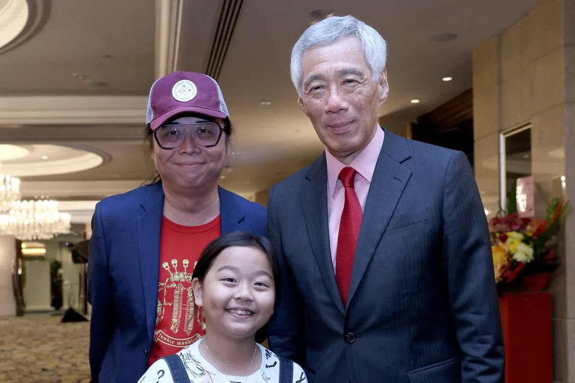 小小音乐人黄姿宁（前）与父亲黄韵仁（左一）受邀在早报百年报庆上演出，演出后与李显龙总理一起合影。（档案照片）