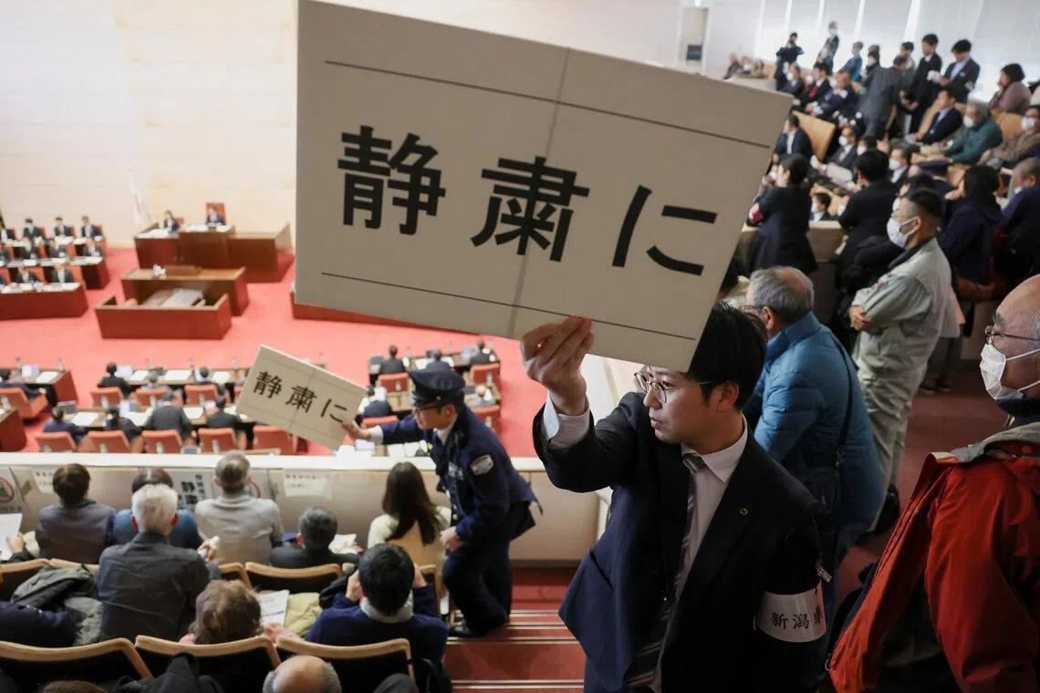 在新潟县议会议员进行投票时，安保人员在旁听席举着写有“请保持安静”的牌子。（路透社）